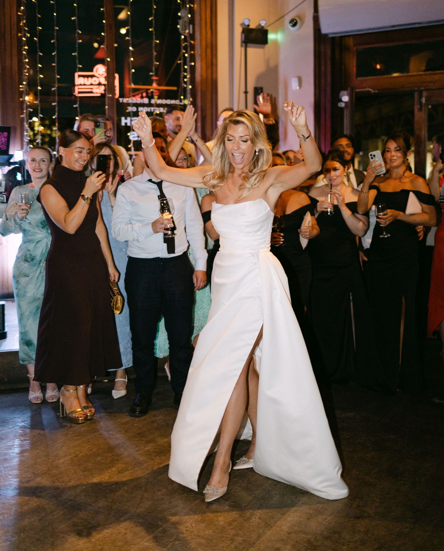 A bride in a white jumpsuit dances during the wedding reception celebration.