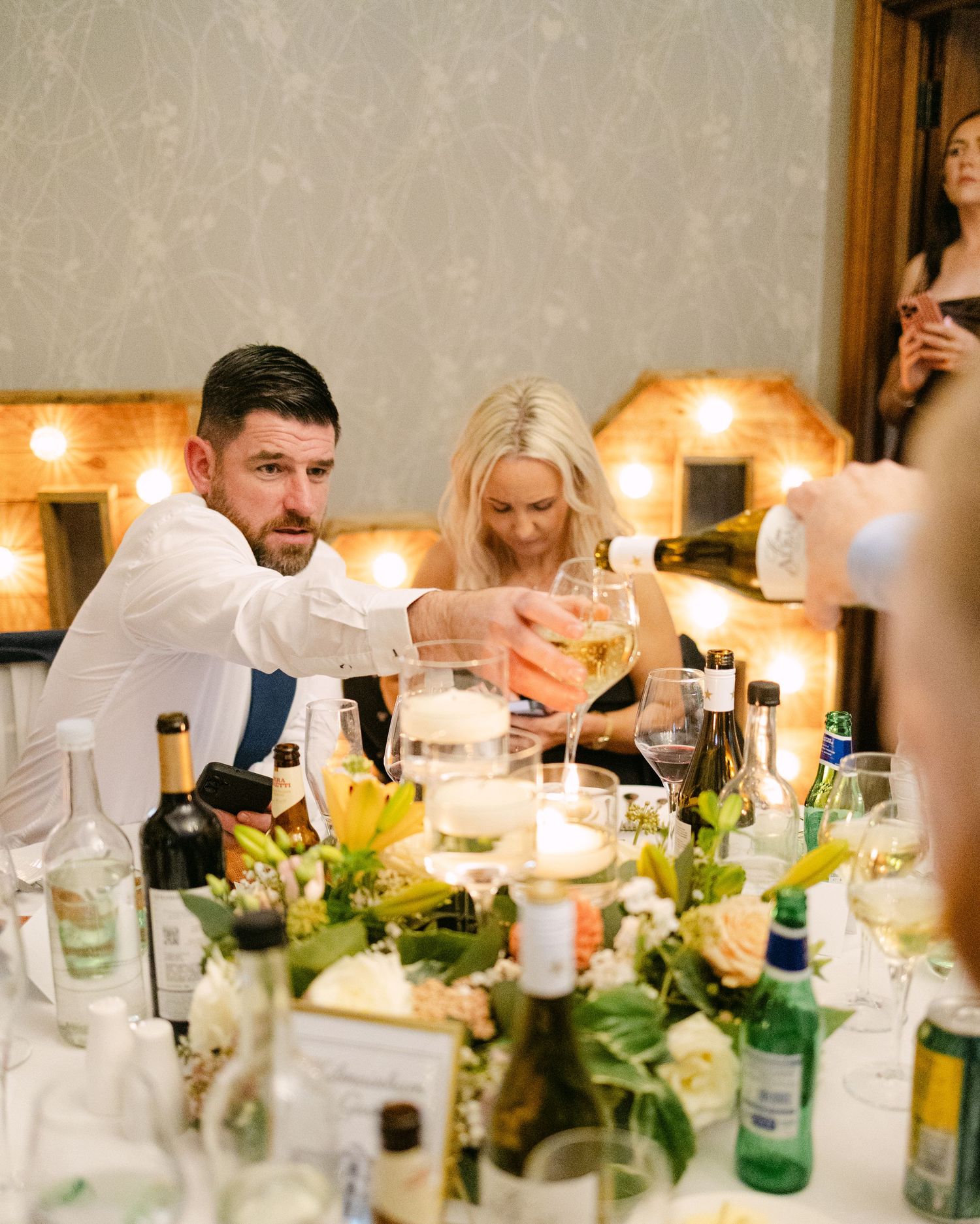 Wedding reception table decorated with greenery and candlelight.