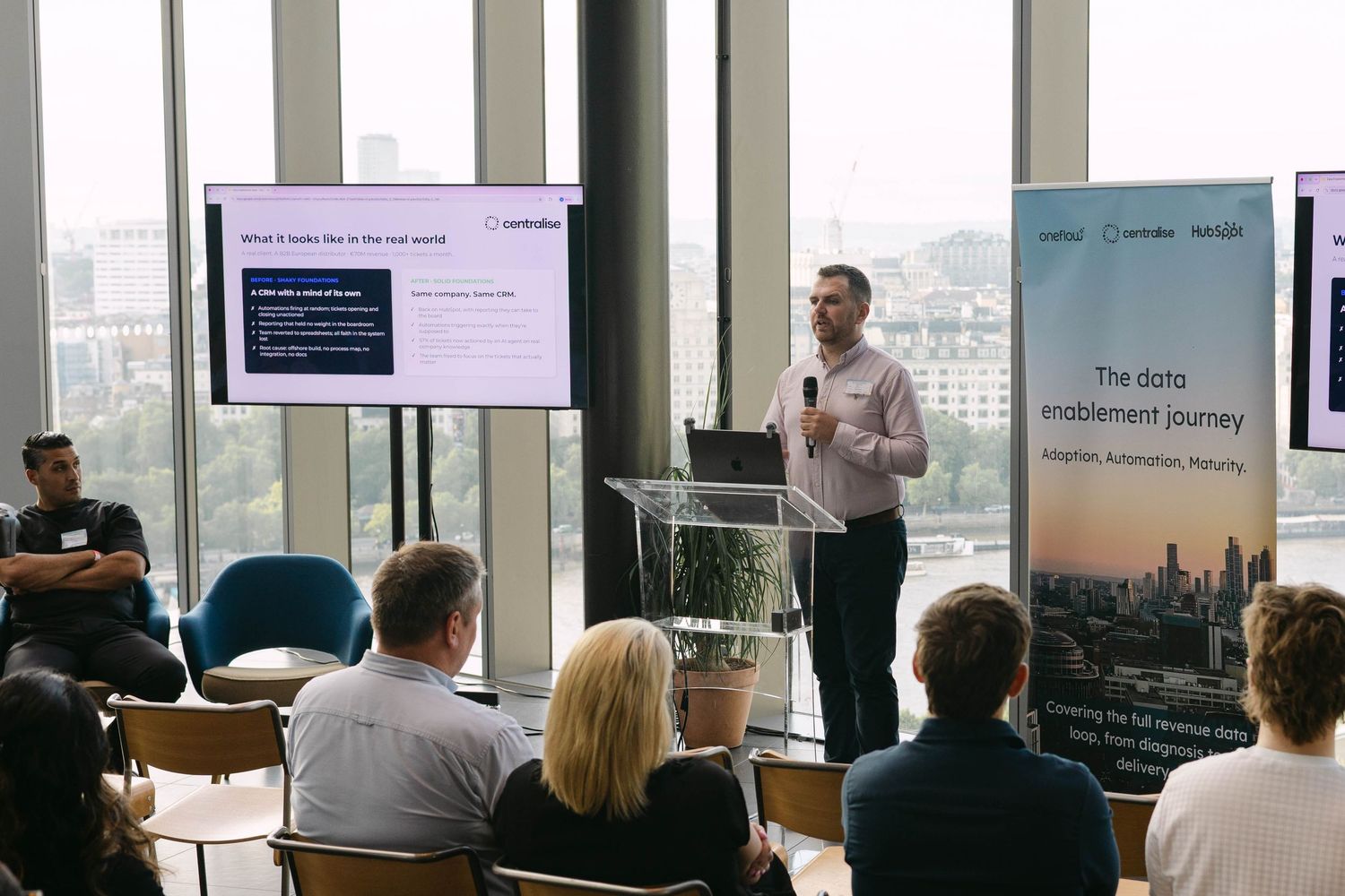 Professional speaker presents data enablement journey at a modern conference with audience and city views.