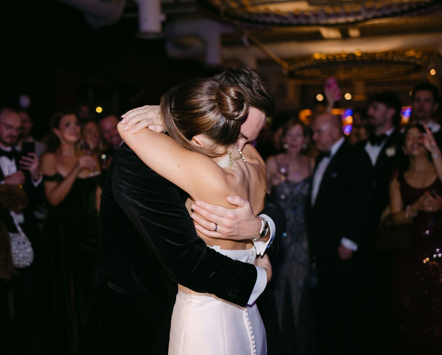 Wedding celebration captured in a dark reception hall with dancing guests.