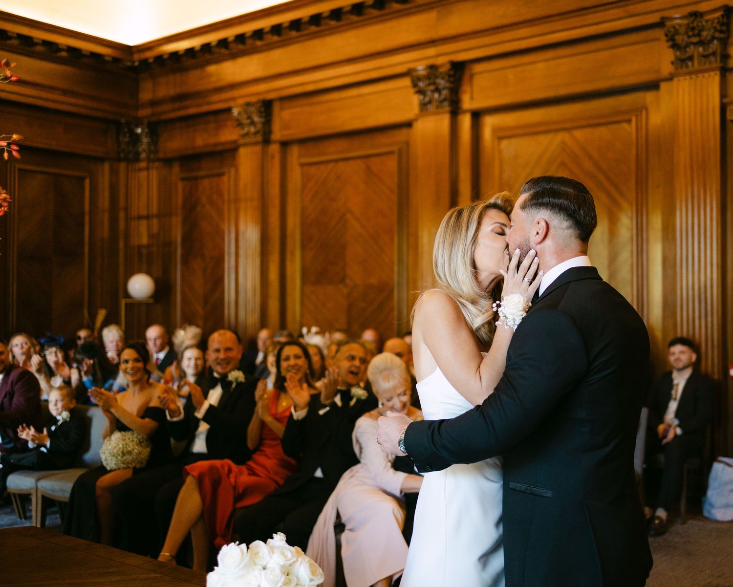 An intimate wedding ceremony moment in a historic venue with wooden paneled walls.