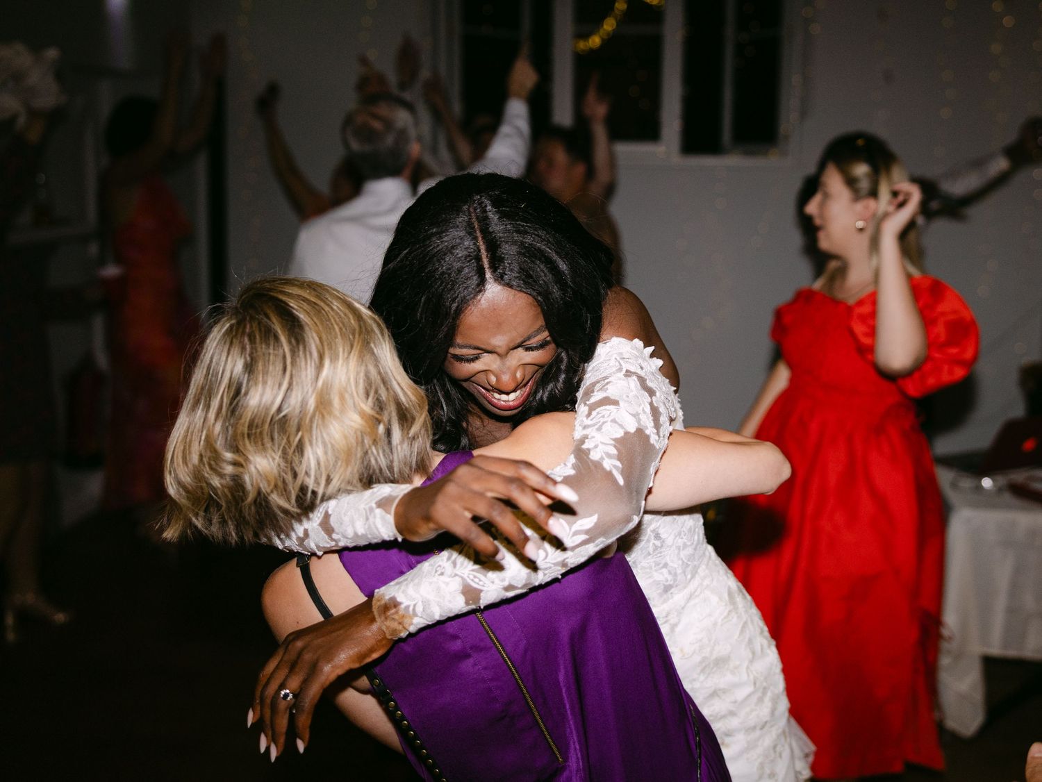 Wedding guests dancing and embracing on the dance floor during a celebration.