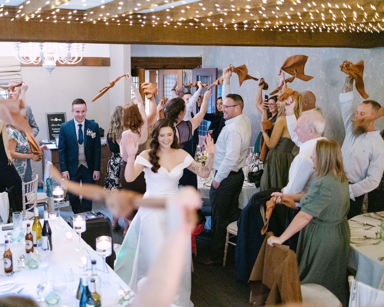Wedding reception venue with string lights and guests celebrating.