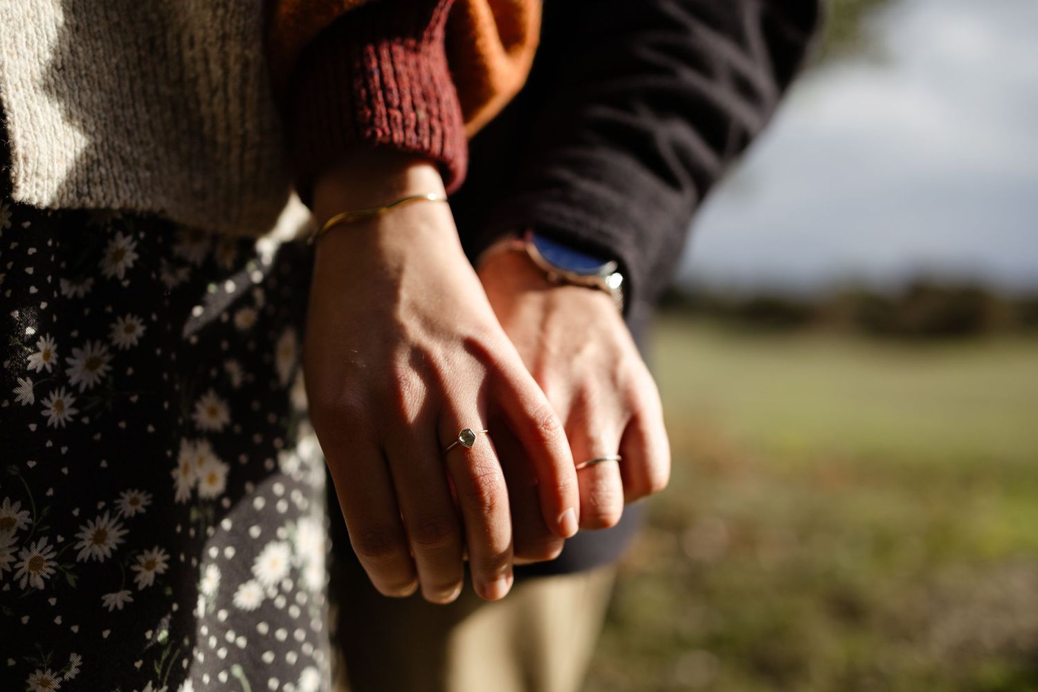 Two hands clasped together against a dark background in an intimate gesture.