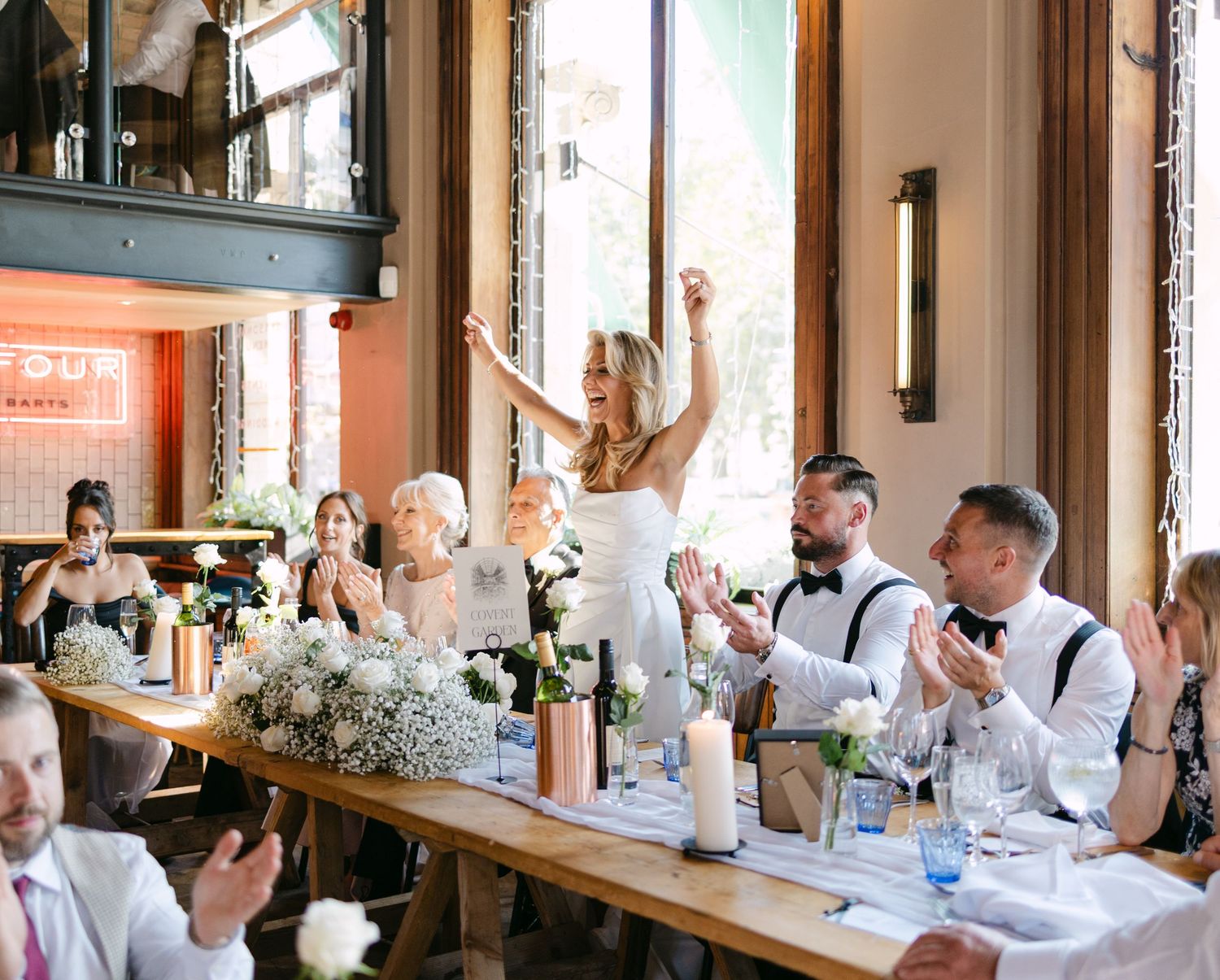 Wedding reception guests seated at long tables with white floral centerpieces.