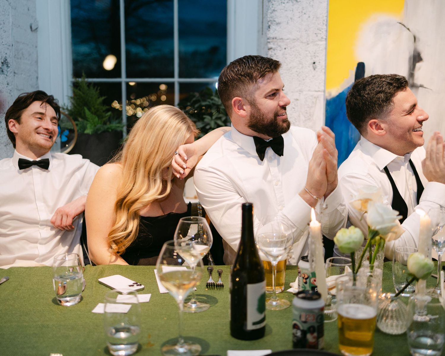 Reception guests posing playfully at a banquet table with colorful drinks.