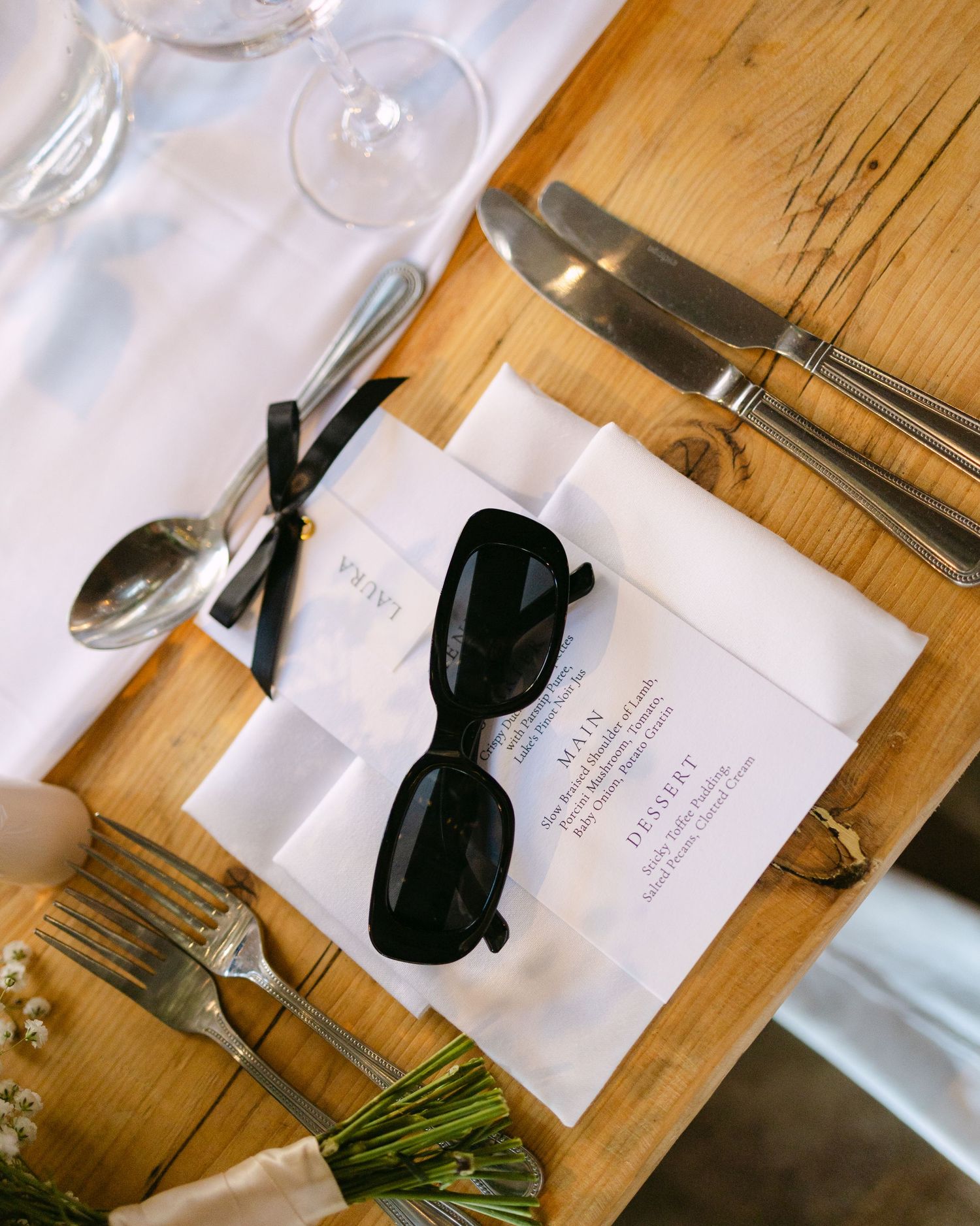 Elegant place settings with black bow ties and name cards on a wooden table.