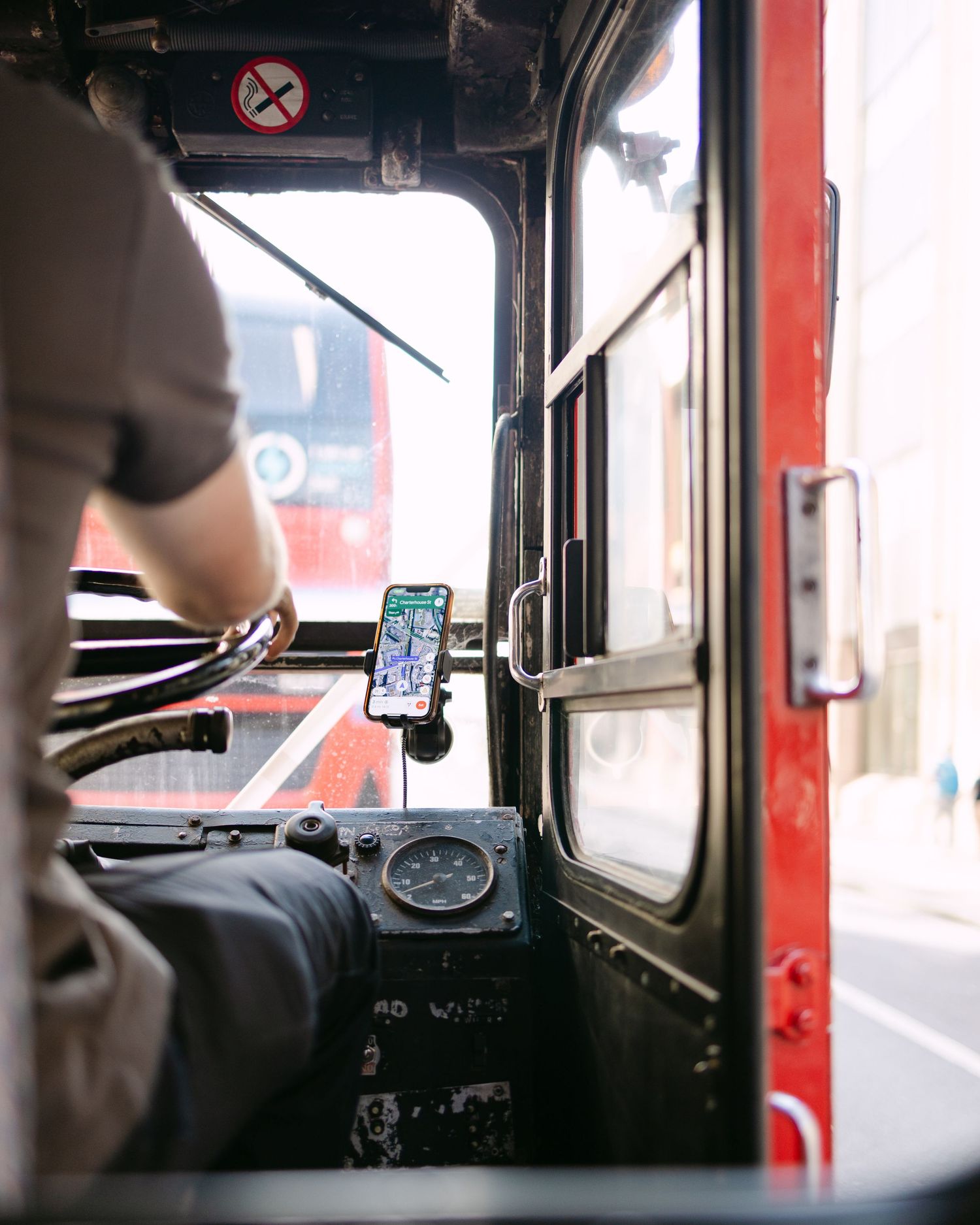 View from inside a vintage red bus or vehicle showing the driver's dashboard and controls.