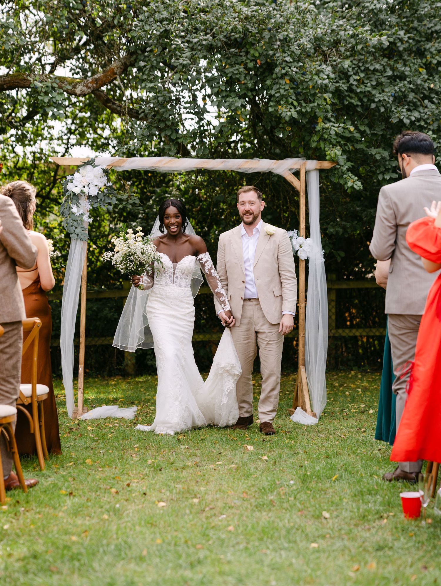 Wedding party and guests gathered on a grassy lawn during an outdoor ceremony.