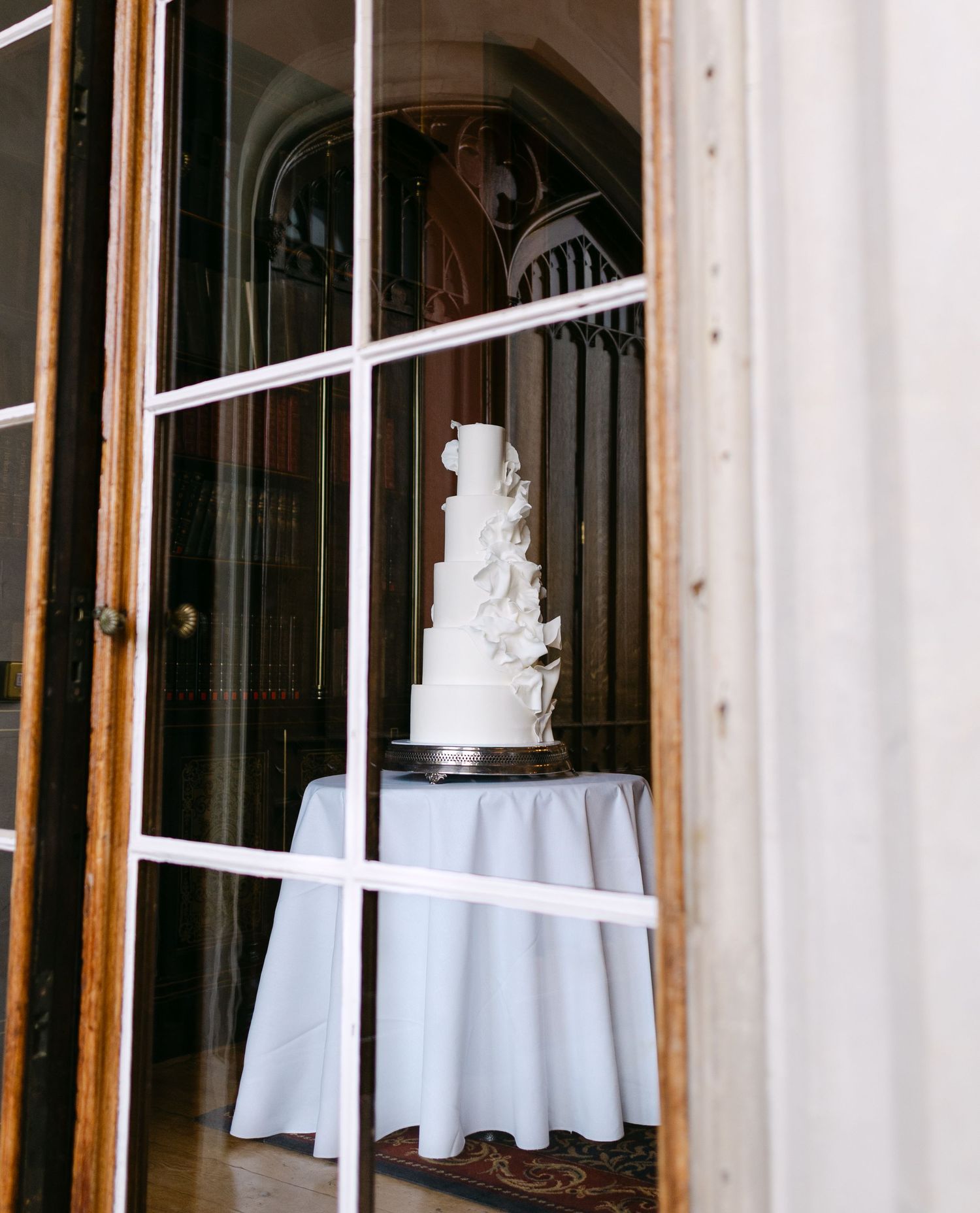 Elegant wedding venue interior with white tablecloths and large windows letting in natural light.