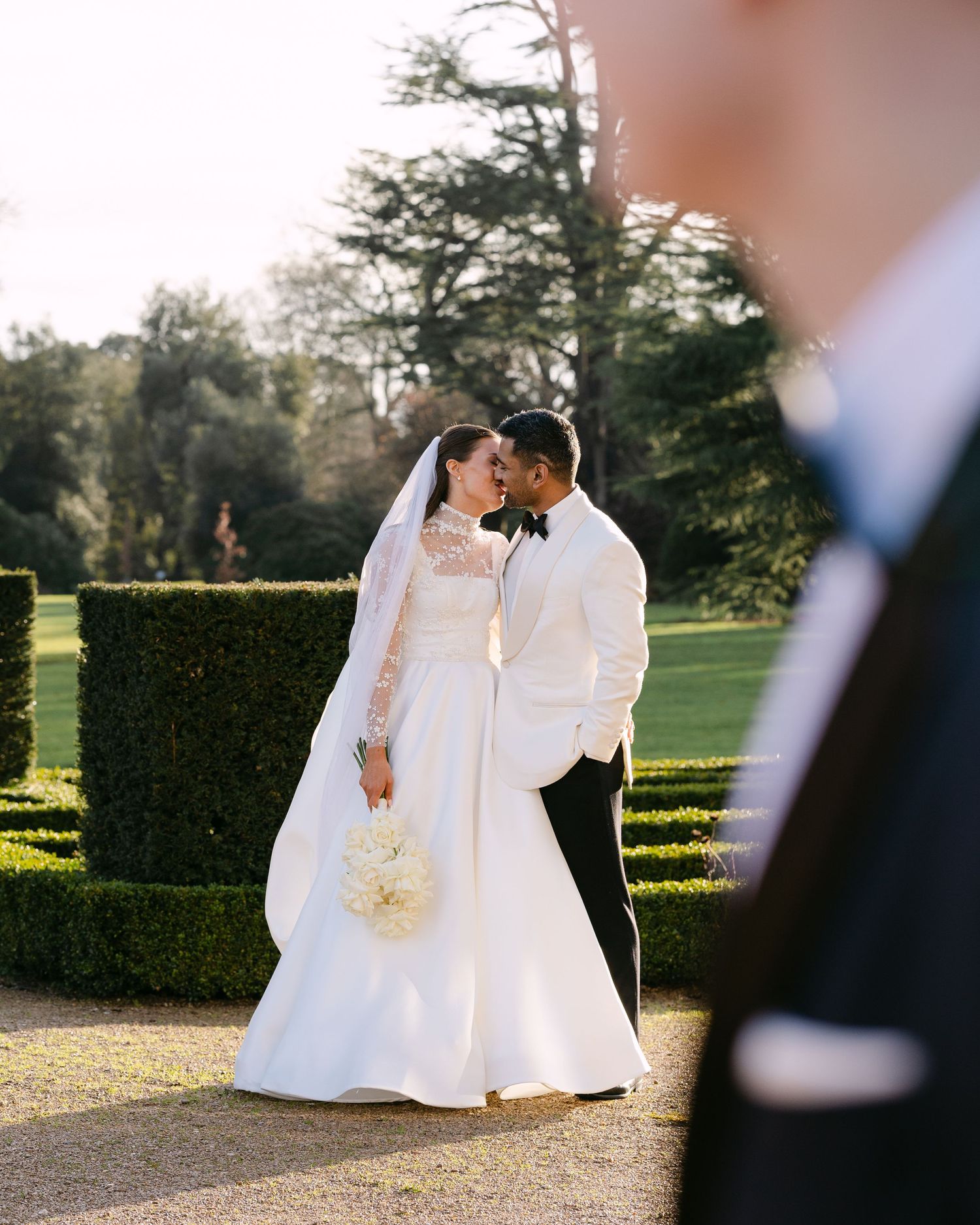 Wedding couple sharing an intimate moment in a manicured garden setting at Ashridge House.