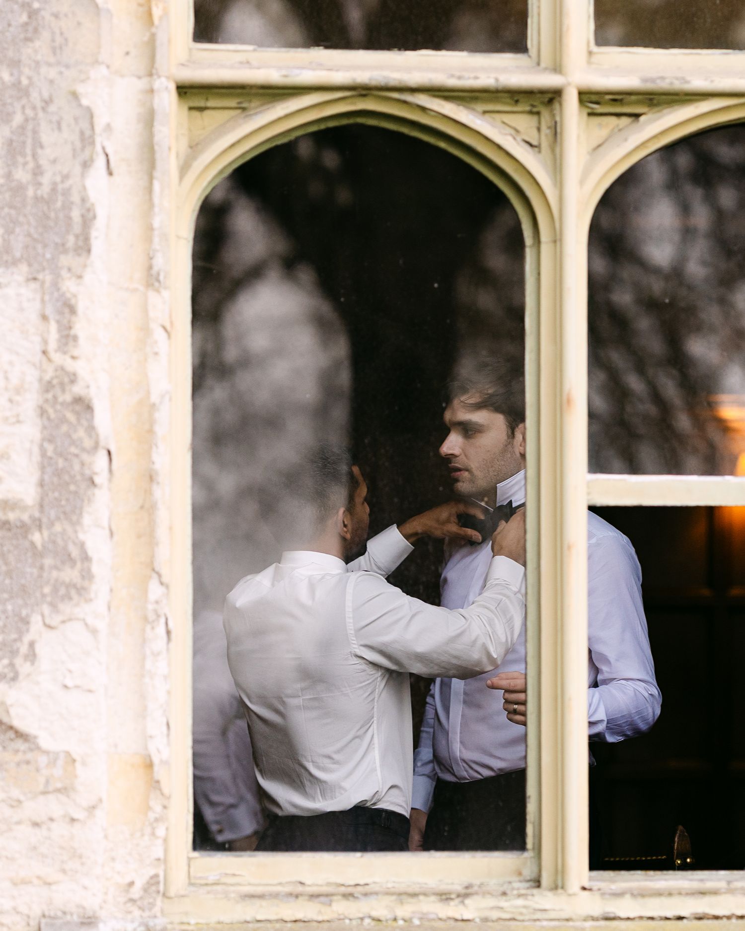 Men in white shirts seen through multiple window panes of a historic building.