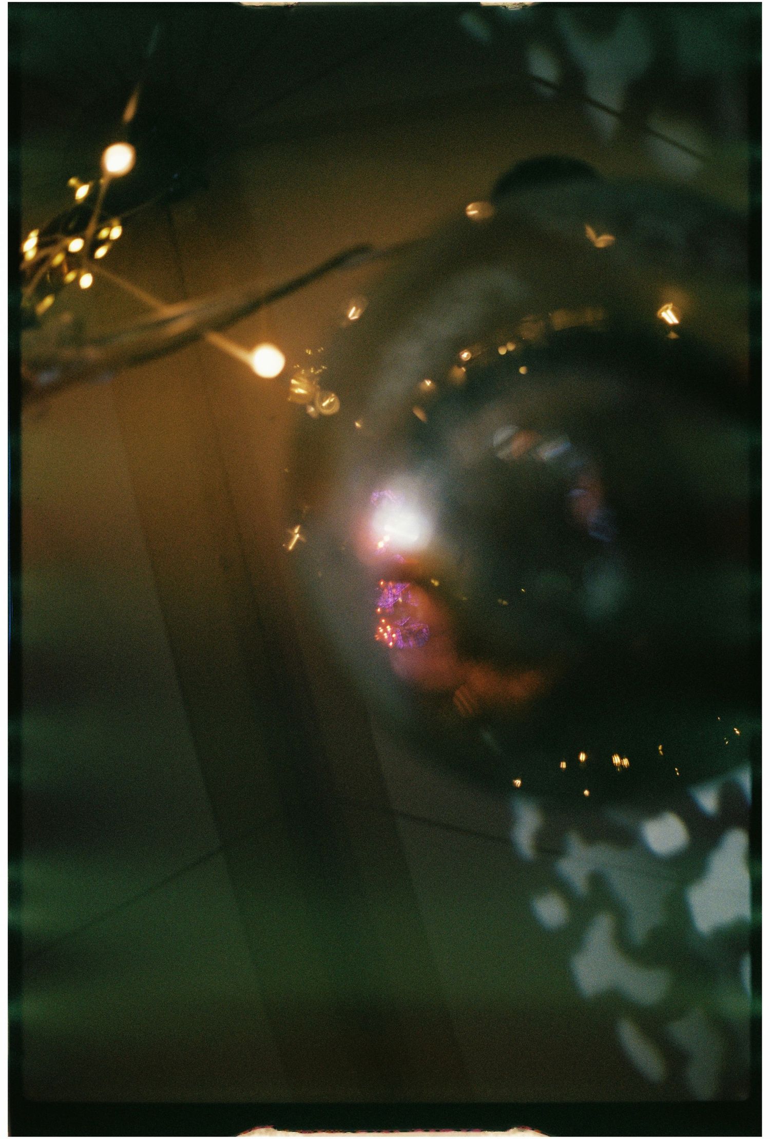 Artistic close-up of a disco ball reflecting warm golden lights among dark foliage at night.