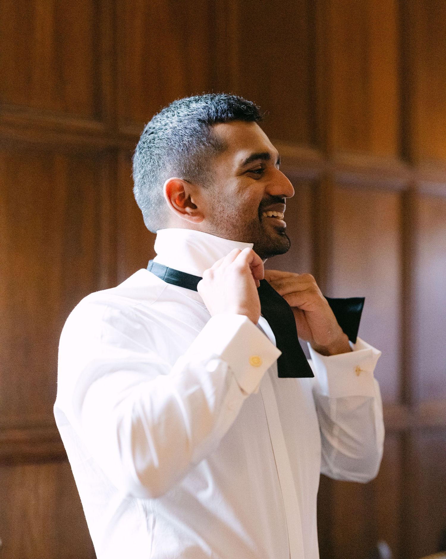 Groomsmen in white dress shirts adjusting their bowties before the ceremony.