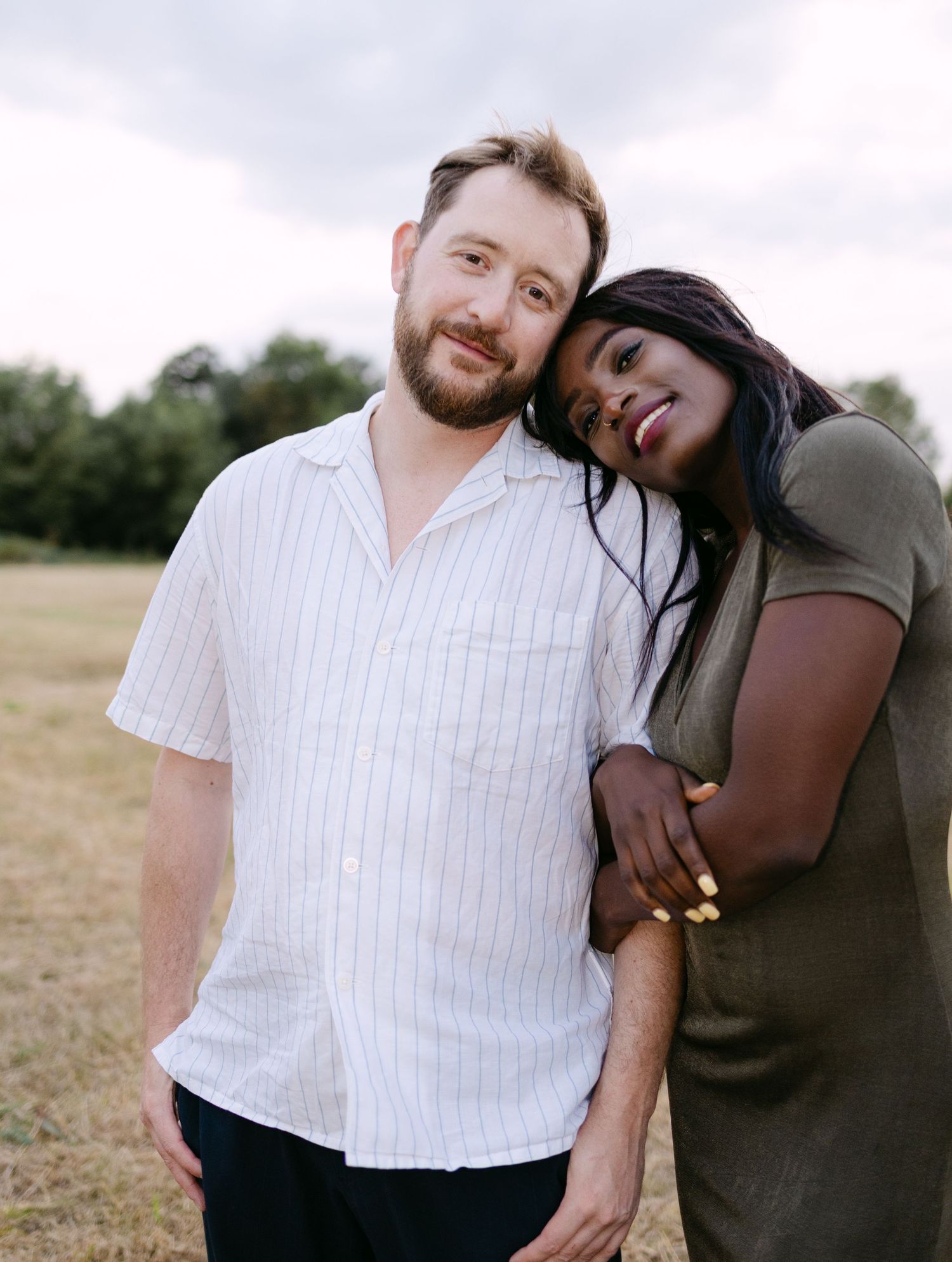 A couple shares intimate moments in a field during a romantic outdoor photo session, captured in a series of candid shots.