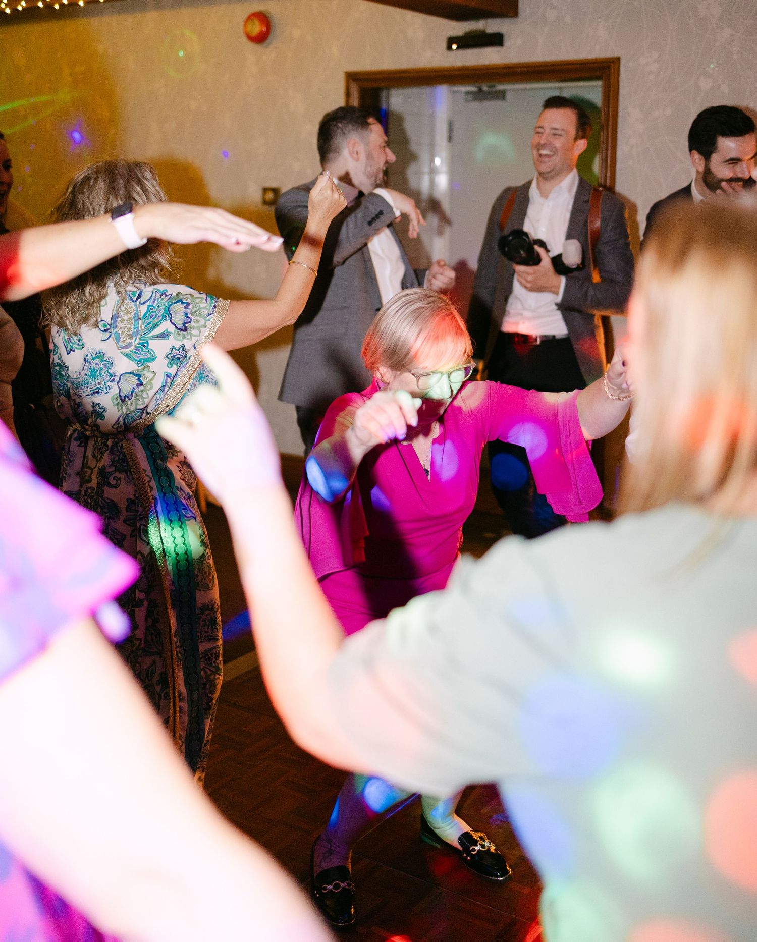 Colorful dance floor scene with party guests celebrating under vibrant lighting.
