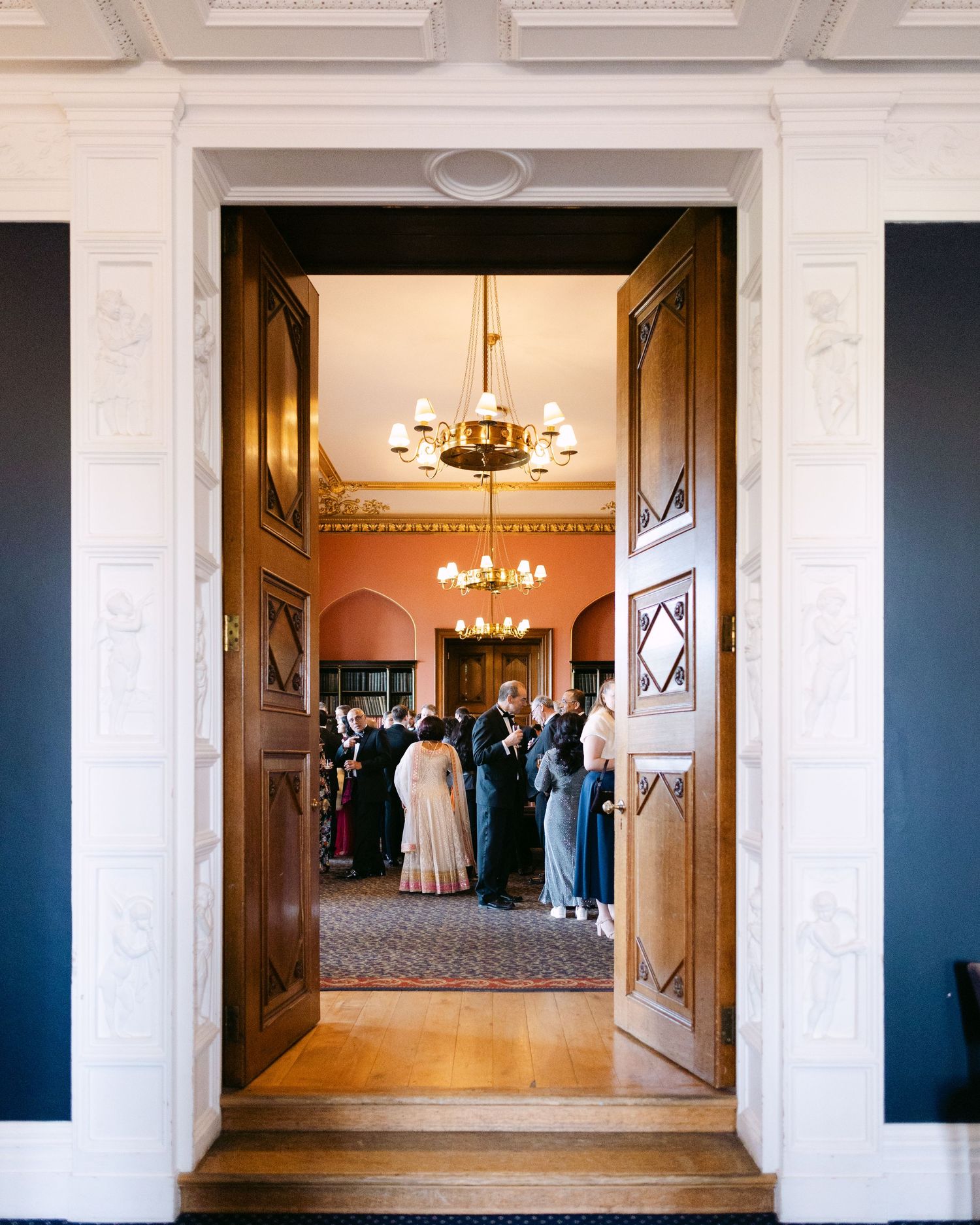 Elegant white interior hallway with chandelier and ornate molding details at Ashridge House, Hertfordshire.