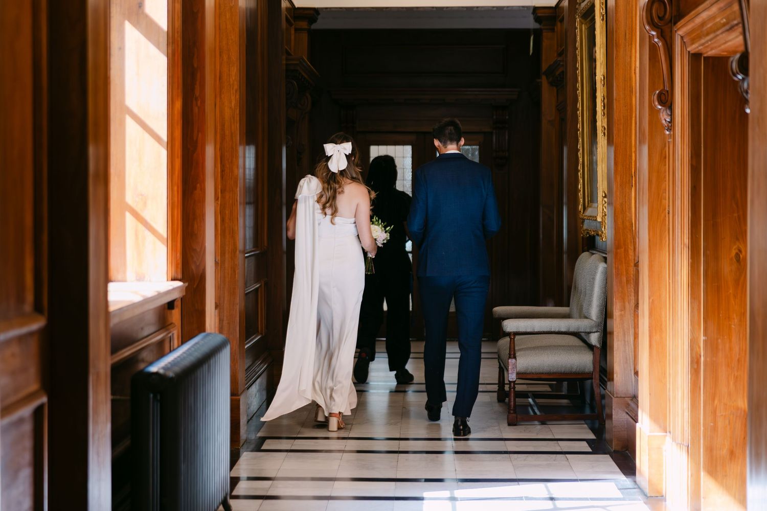 Bride and groom walking with registrar down corridor at Old Marylebone Town Hall in London