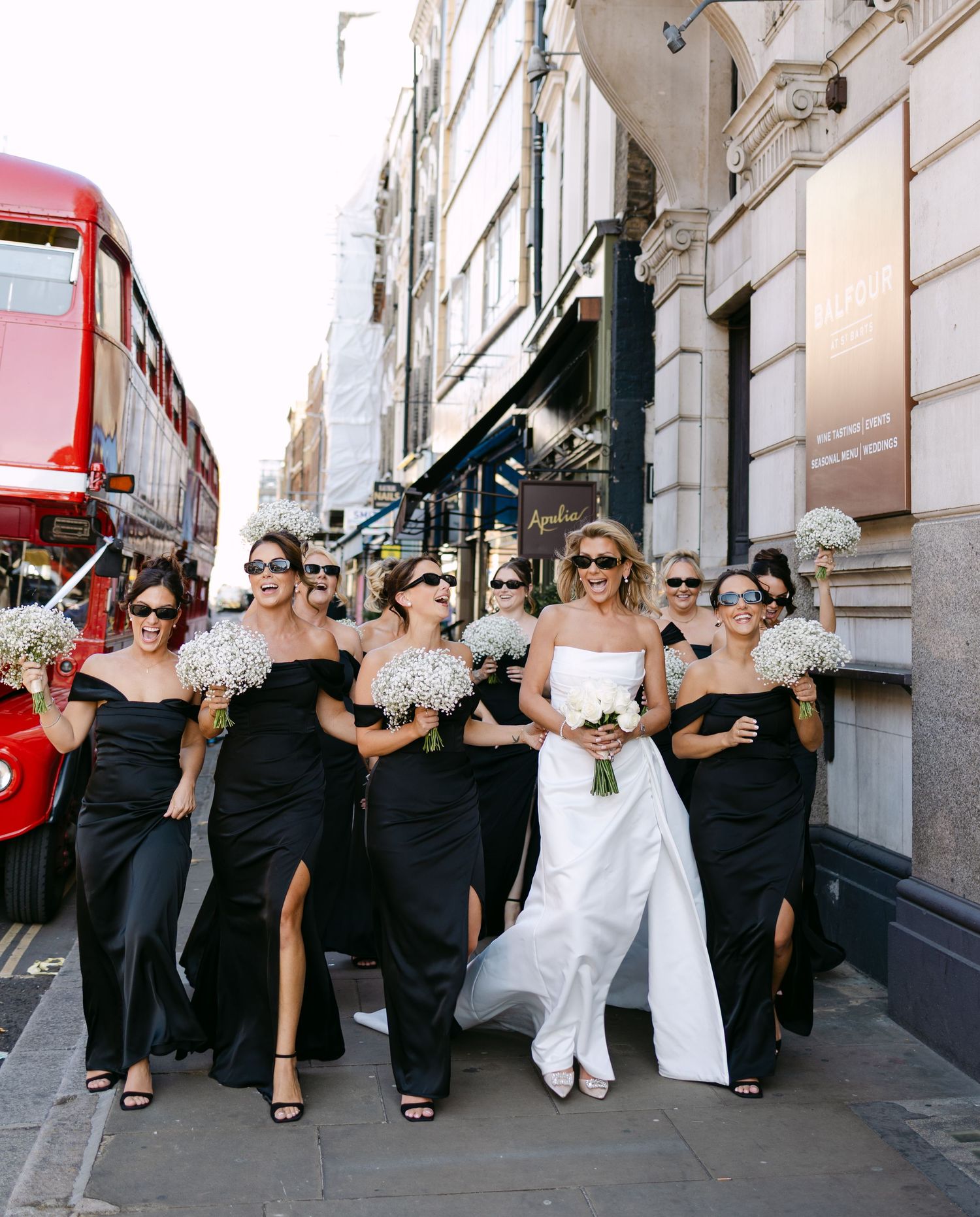 A group in black and white attire poses together in a playful line formation on a city street.