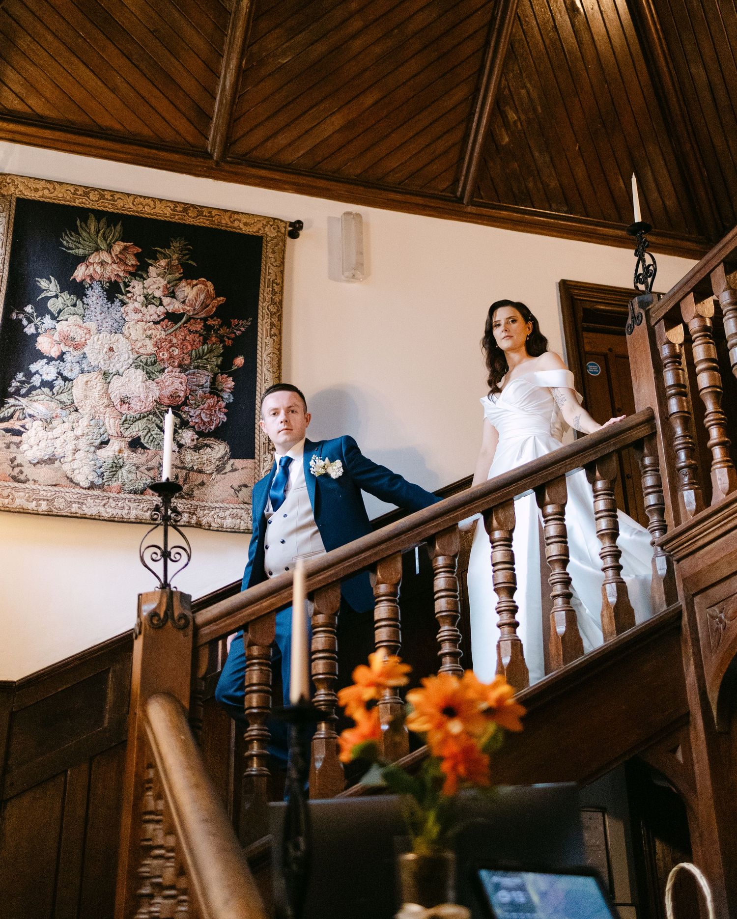 Wedding photos on a wooden staircase with vintage floral artwork in the background.