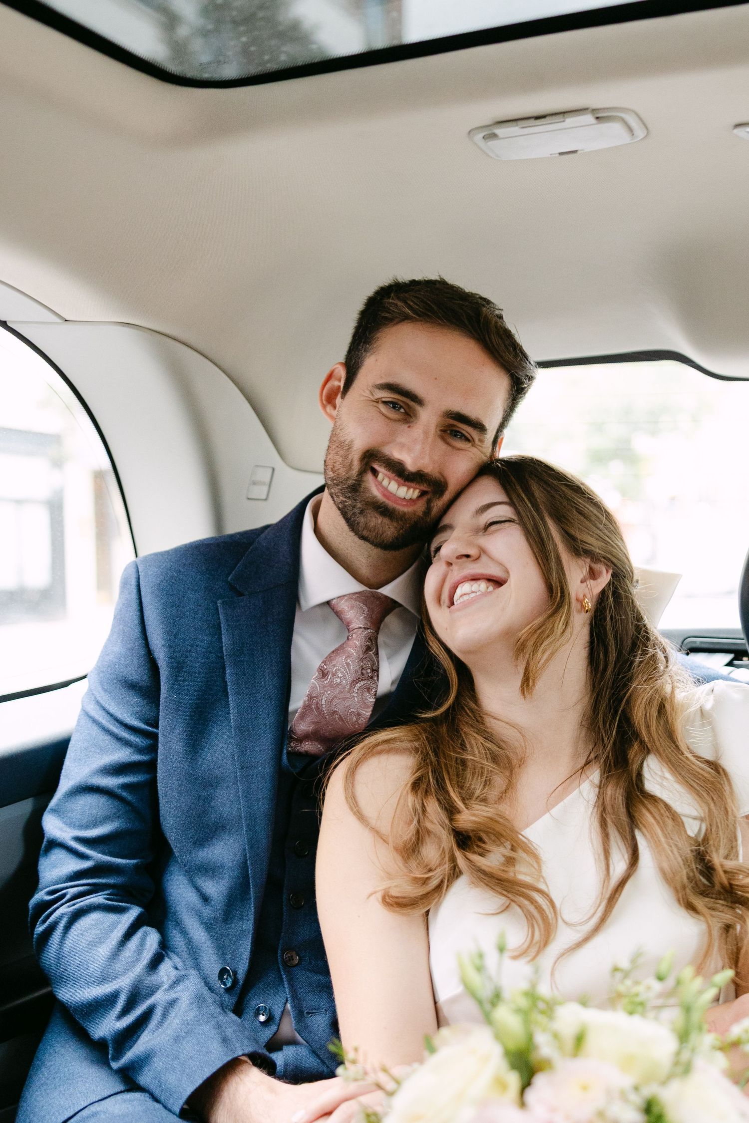 A happy couple shares intimate moments and laughter while sitting together in the backseat of a taxi.