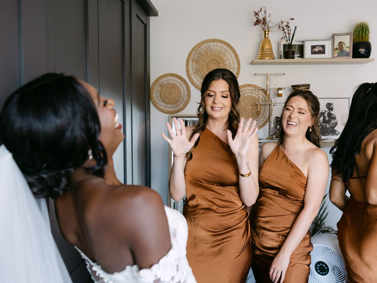 Wedding party members in brown dresses share a celebratory moment during preparations.