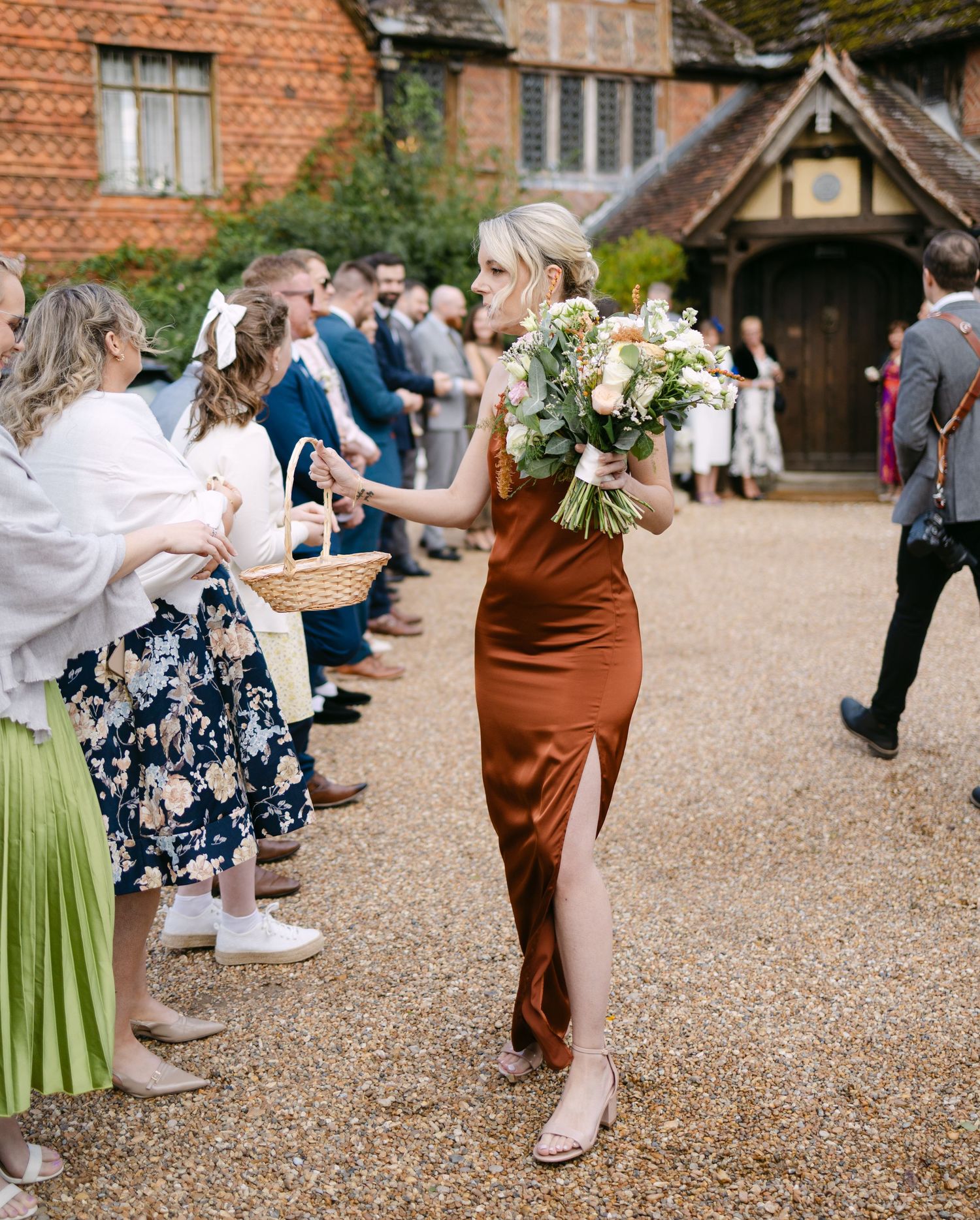 Wedding guests play a lawn game outside a historic brick building.