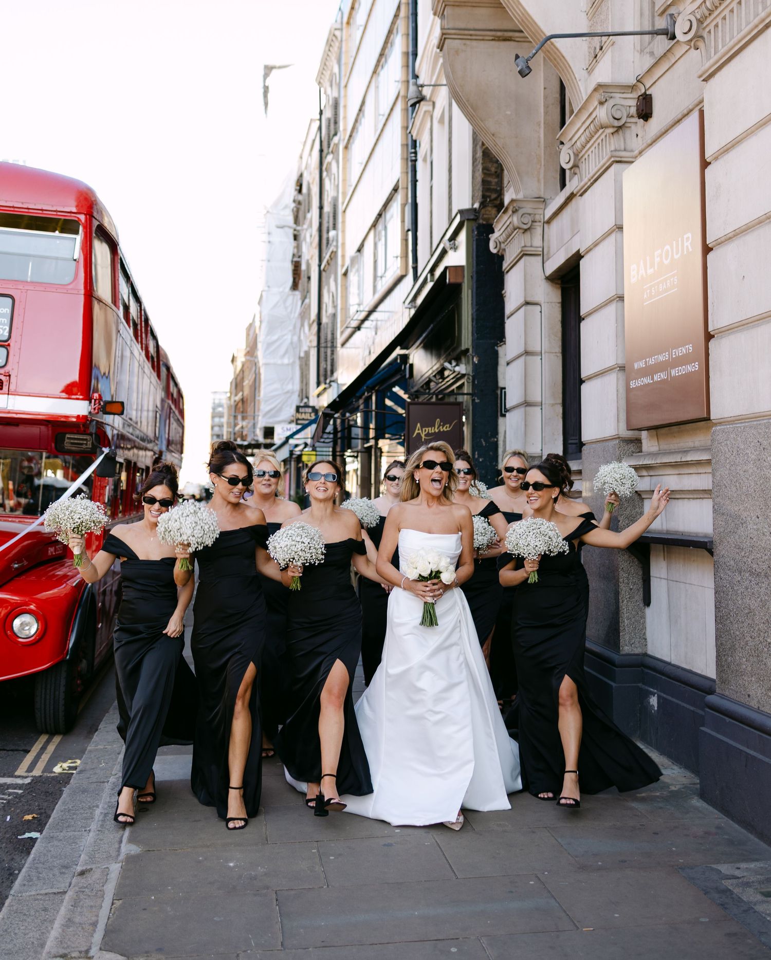 Wedding party poses playfully on a city street wearing formal attire.