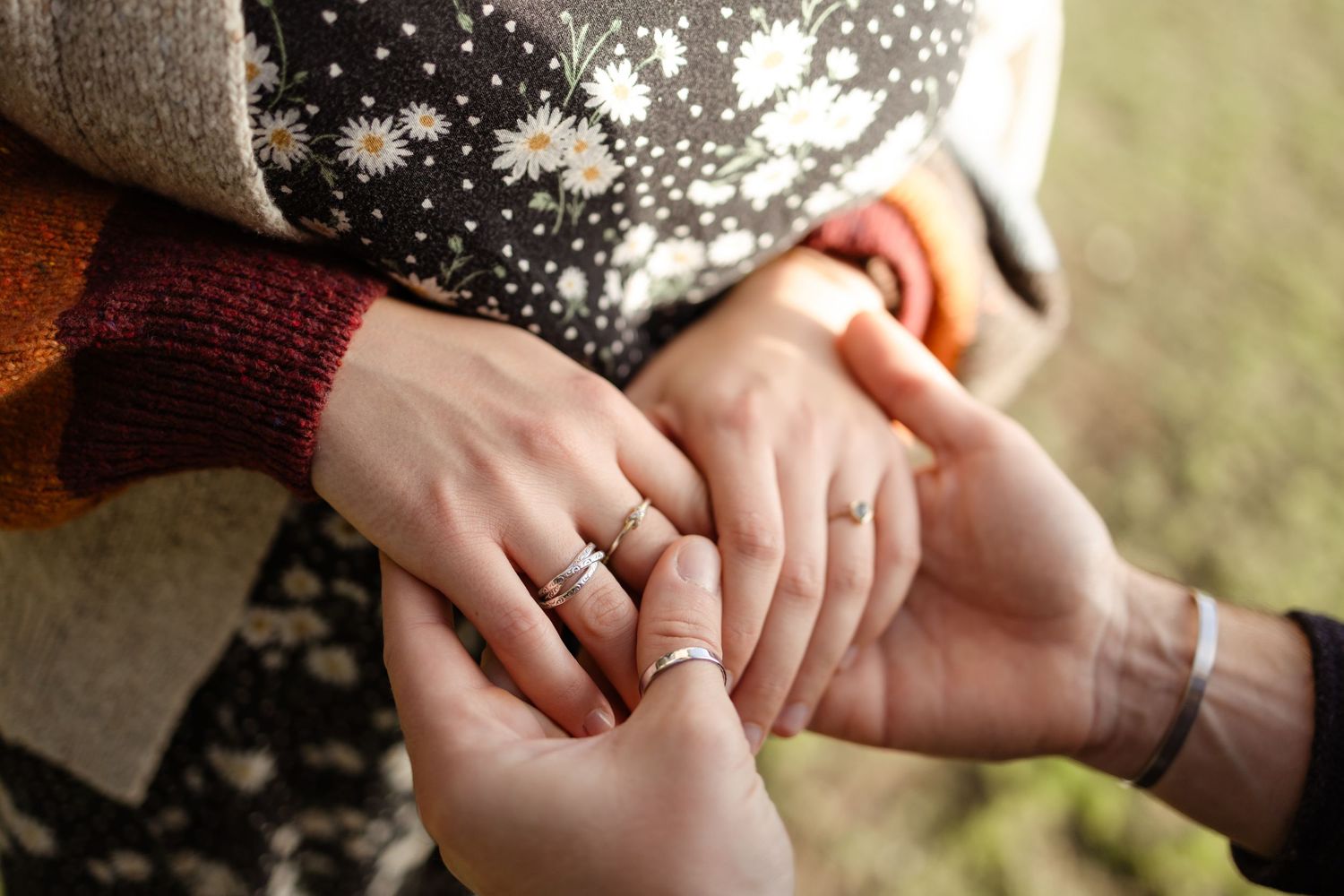 Close-up shot of hands showing off engagement rings in natural lighting.