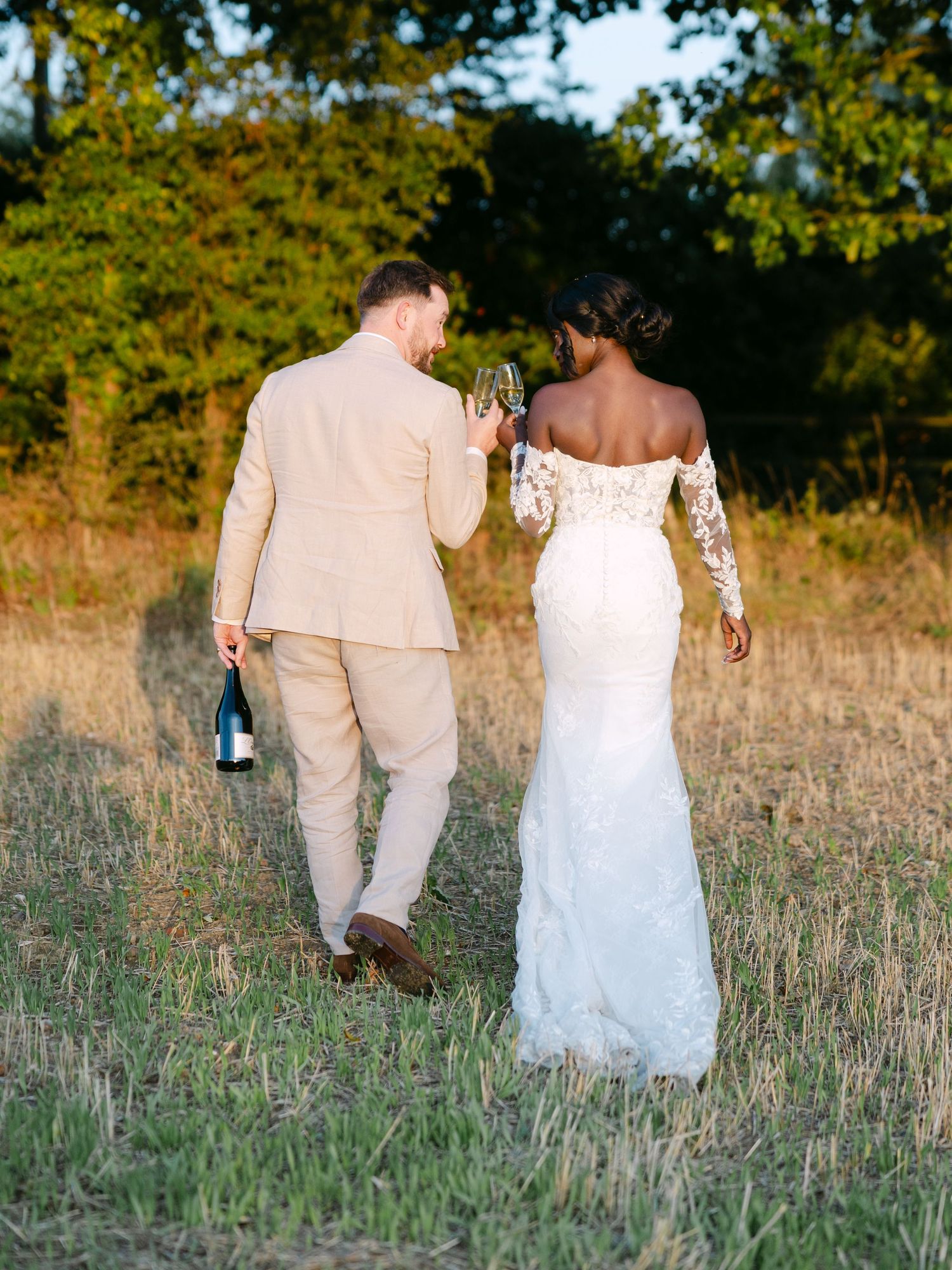A couple shares a romantic moment in a field at sunset during their wedding celebration.