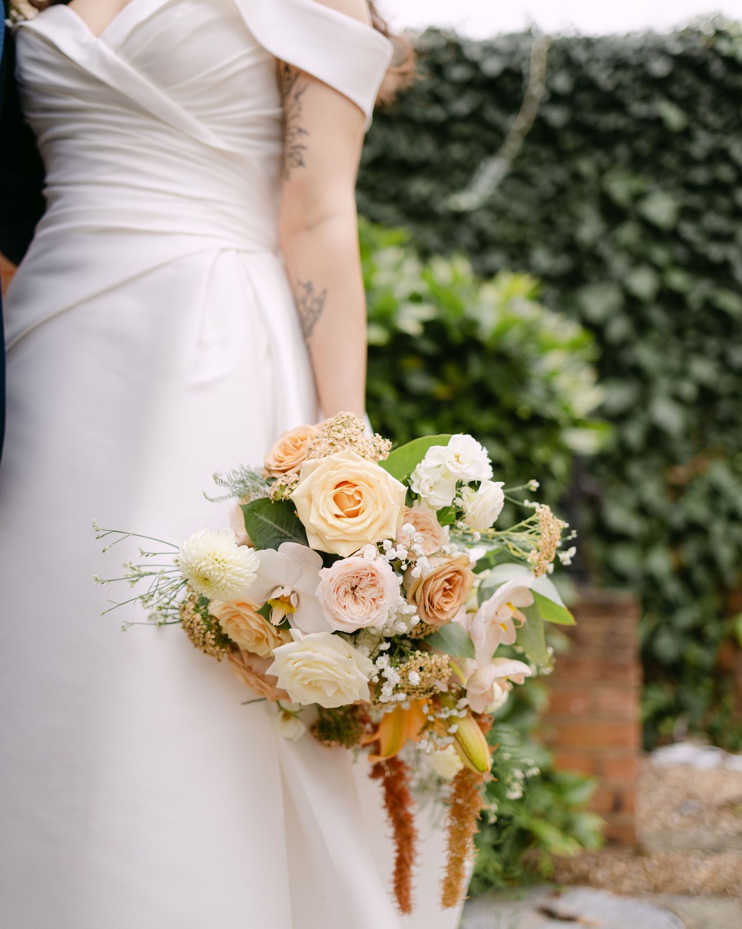 Close-up details of a peach and cream wedding bouquet with roses and delicate foliage.