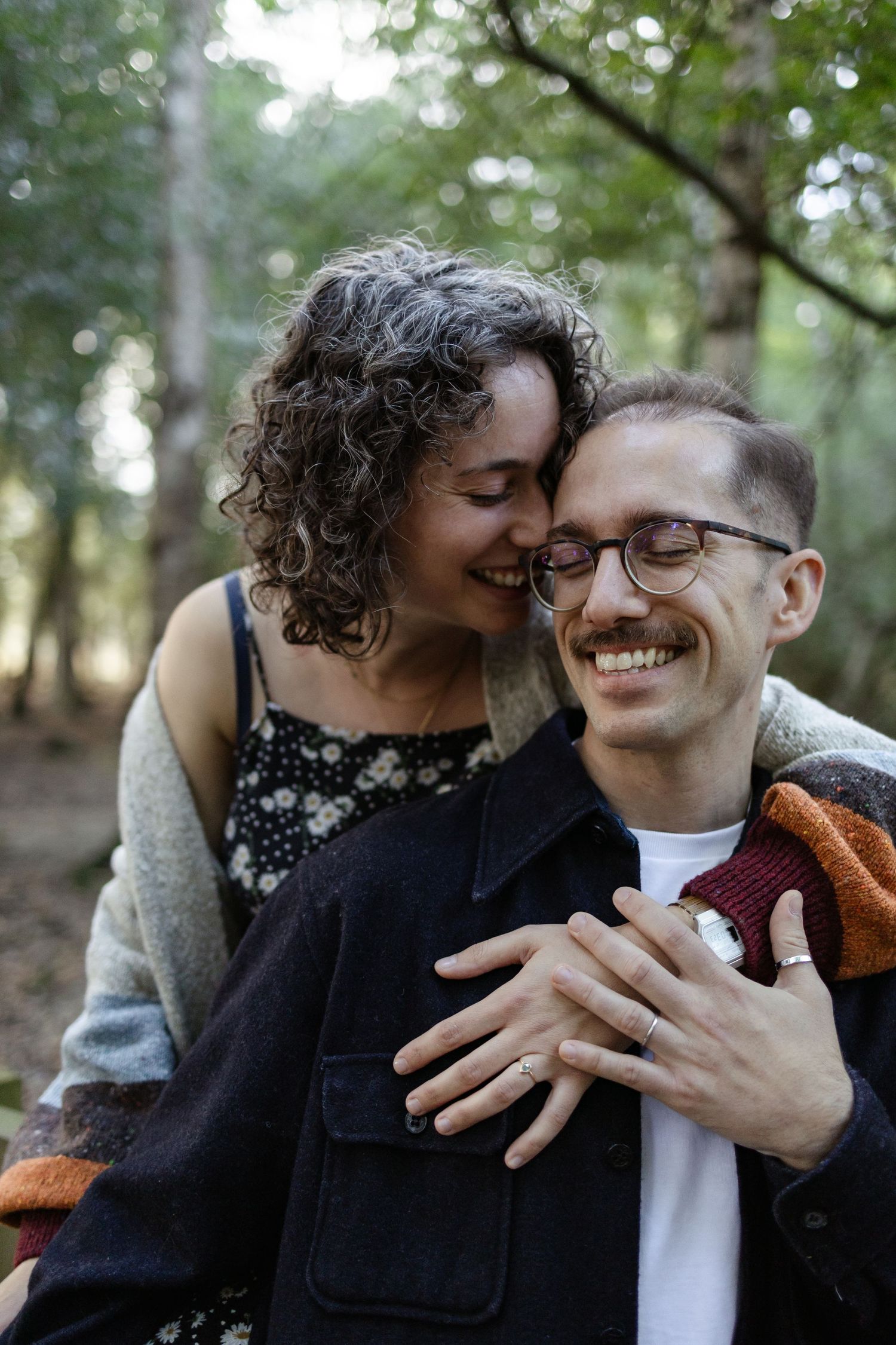 A joyful couple sharing an intimate moment in a forest setting.