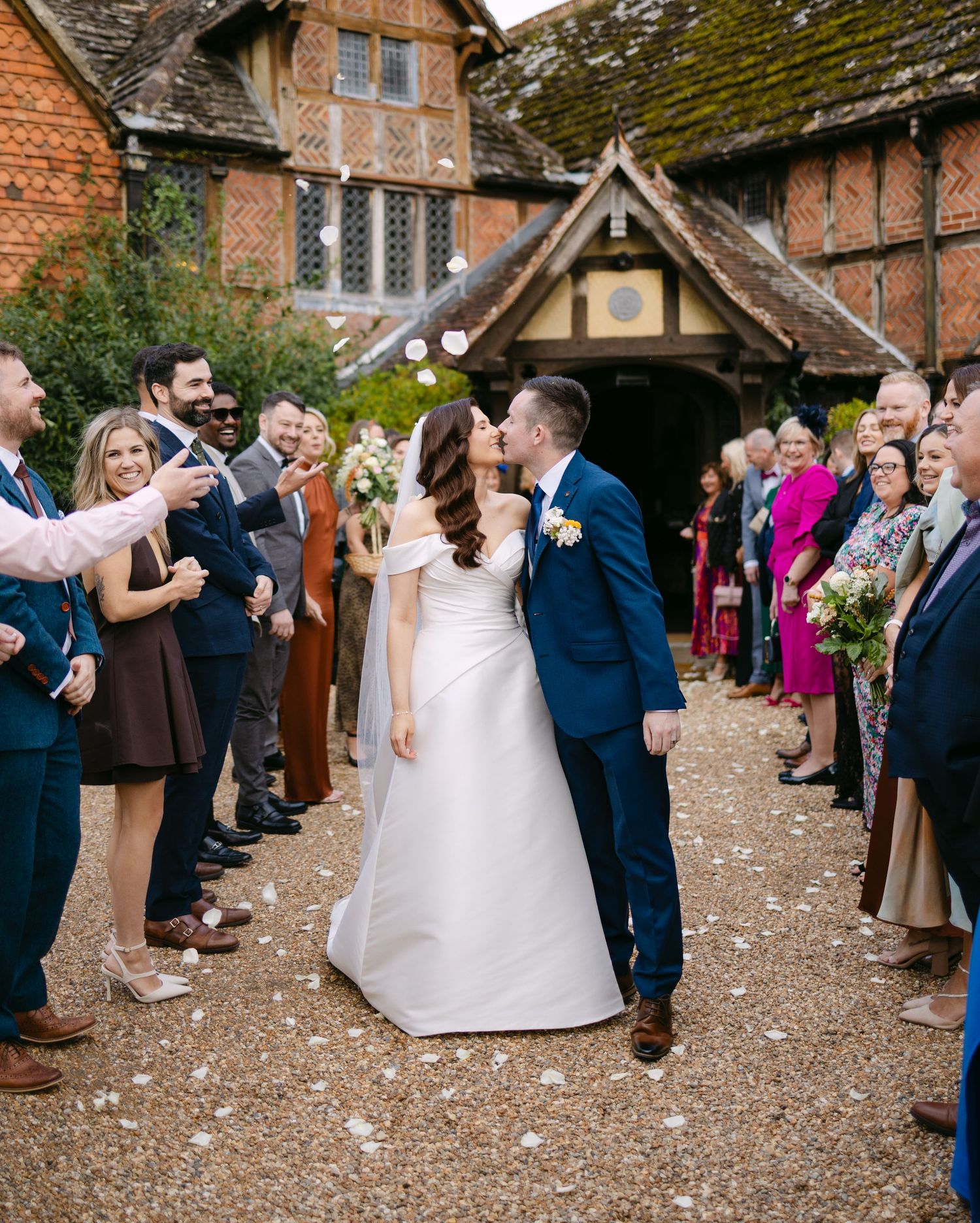 Guests throw confetti at a wedding celebration outside a historic brick building.