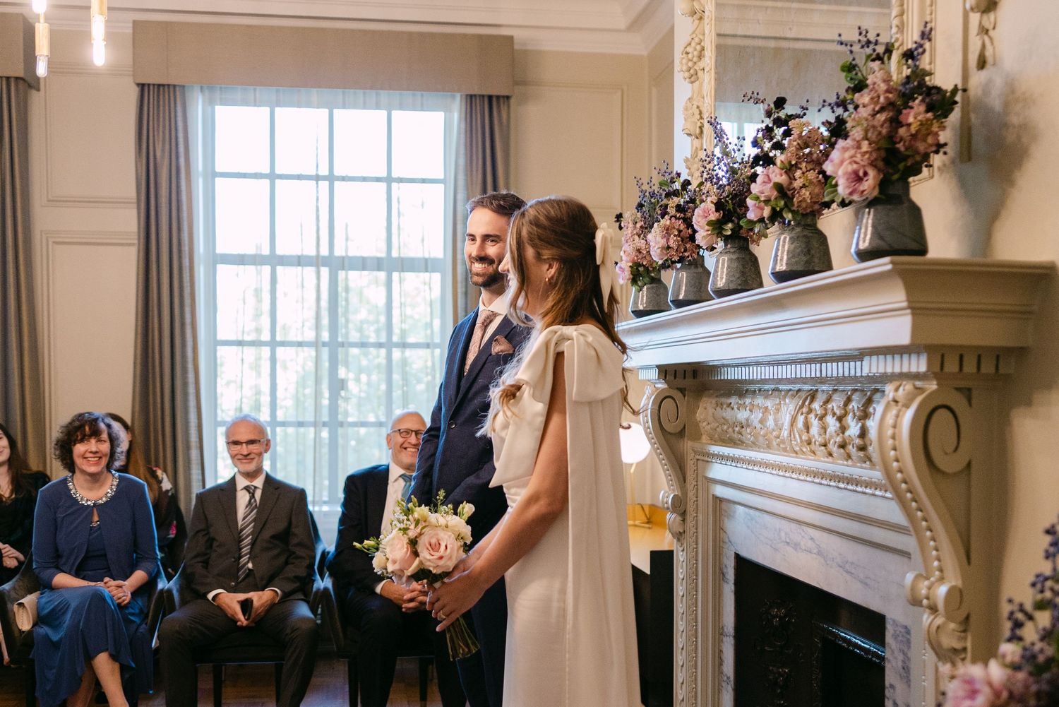 Wedding ceremony attendees gather in the Pimlico Room at The Old Marylebone Town Hall.