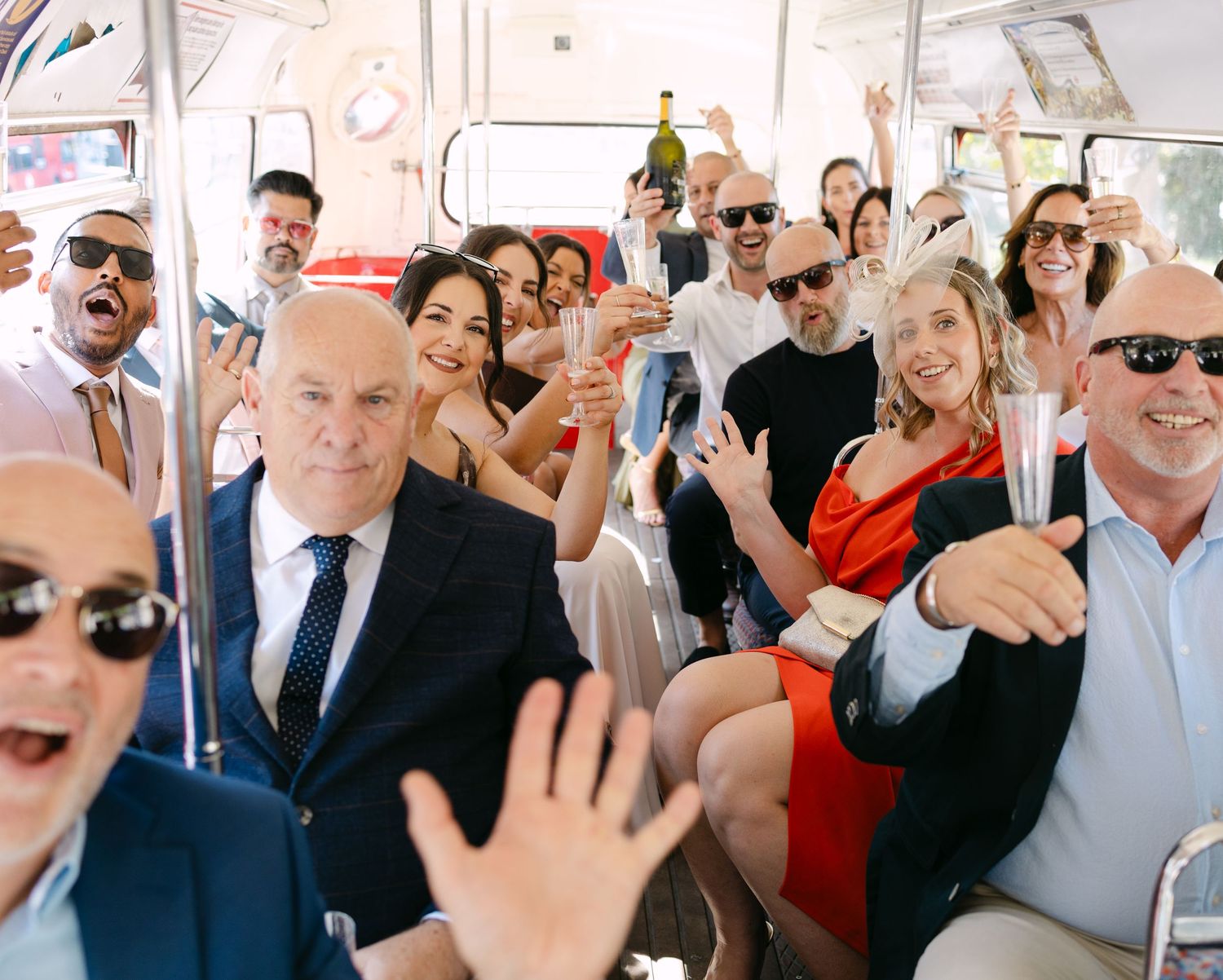 Passengers on public transportation smiling and waving at the camera during a celebratory moment.