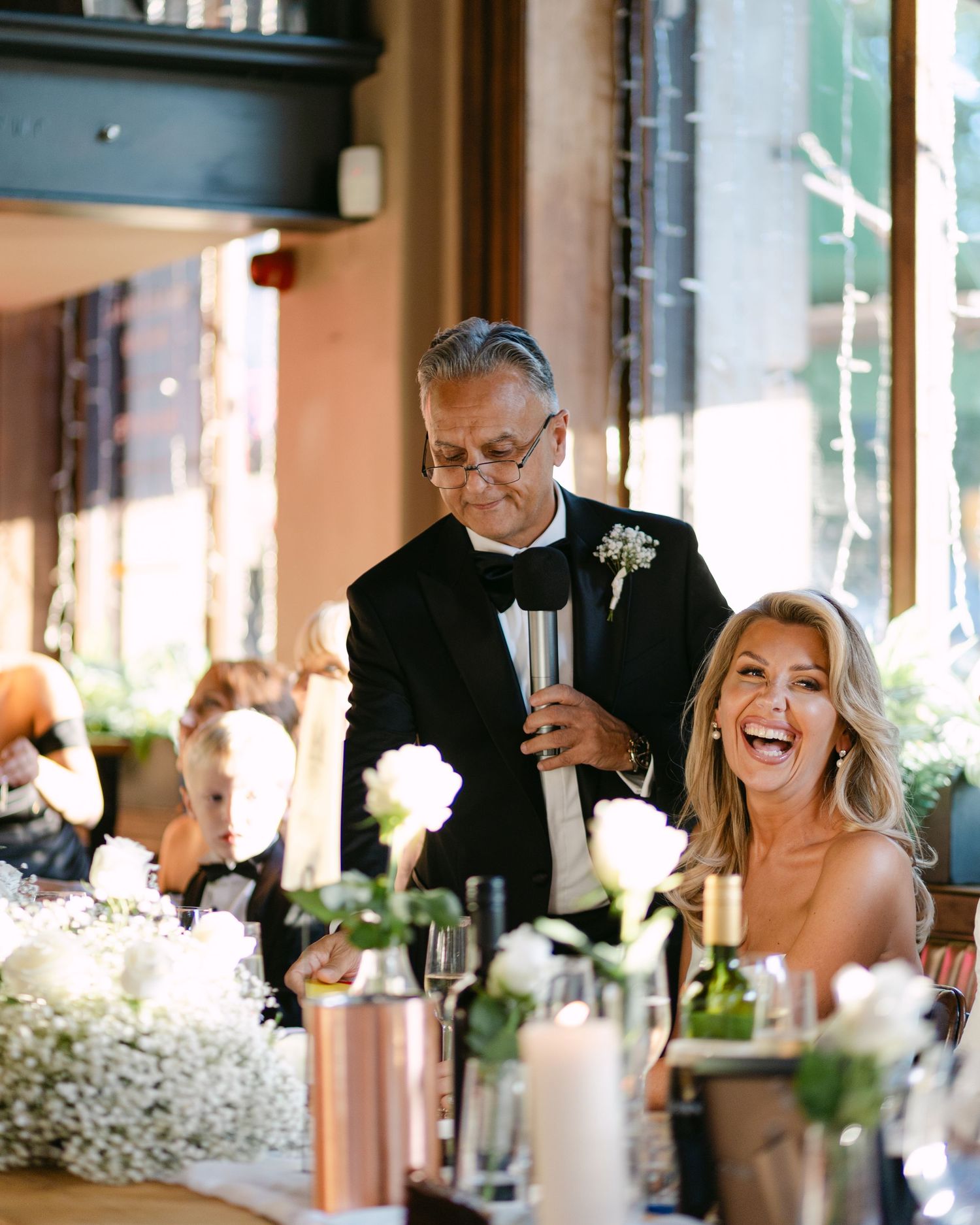 A celebratory moment during wedding speeches at an elegant indoor reception.