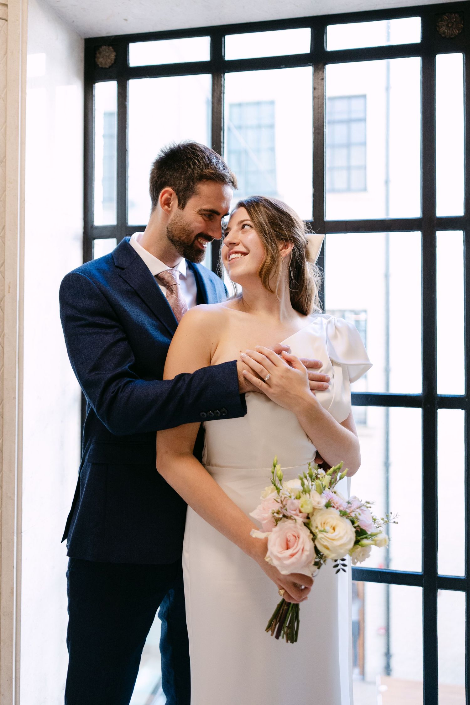 A romantic wedding couple shares intimate moments in a series of photos against a bright windowed backdrop.