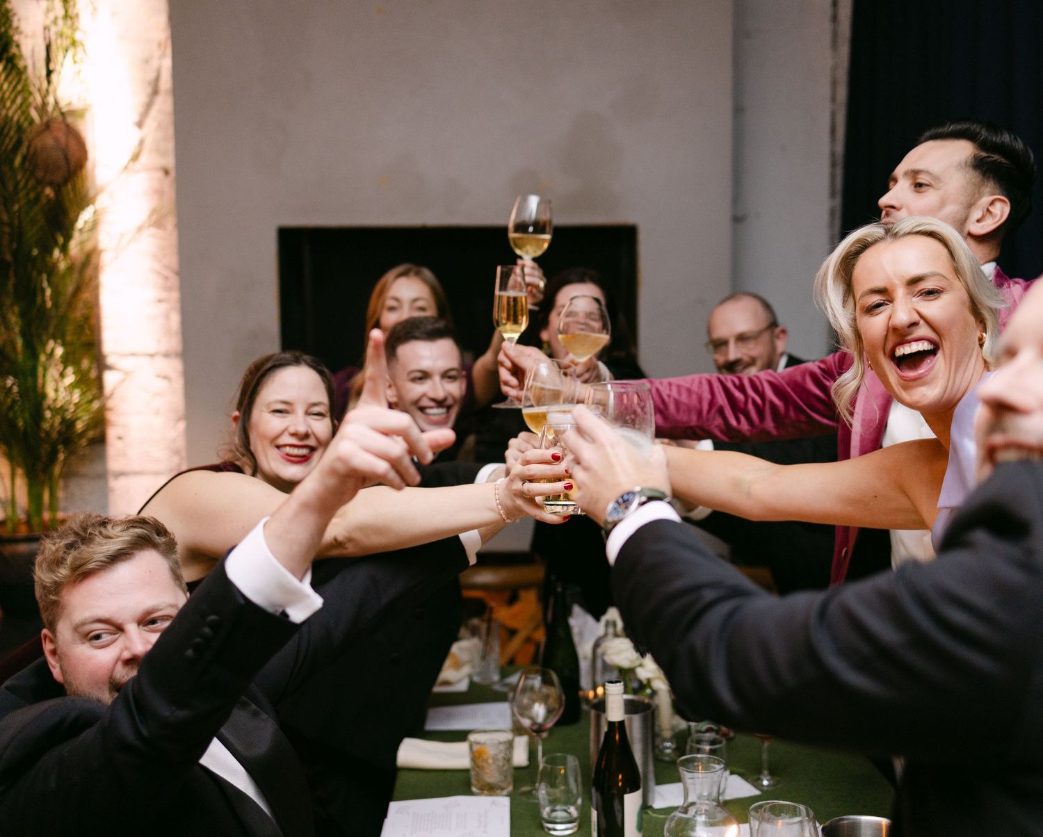 Joyful celebration with guests raising their arms in excitement at a wedding reception.