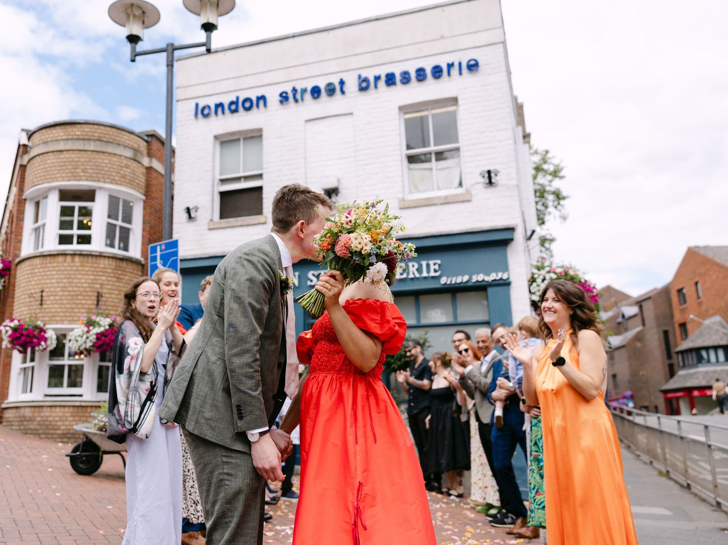 Newlyweds celebrate outside London Street Brasserie with guests lining the sidewalk.