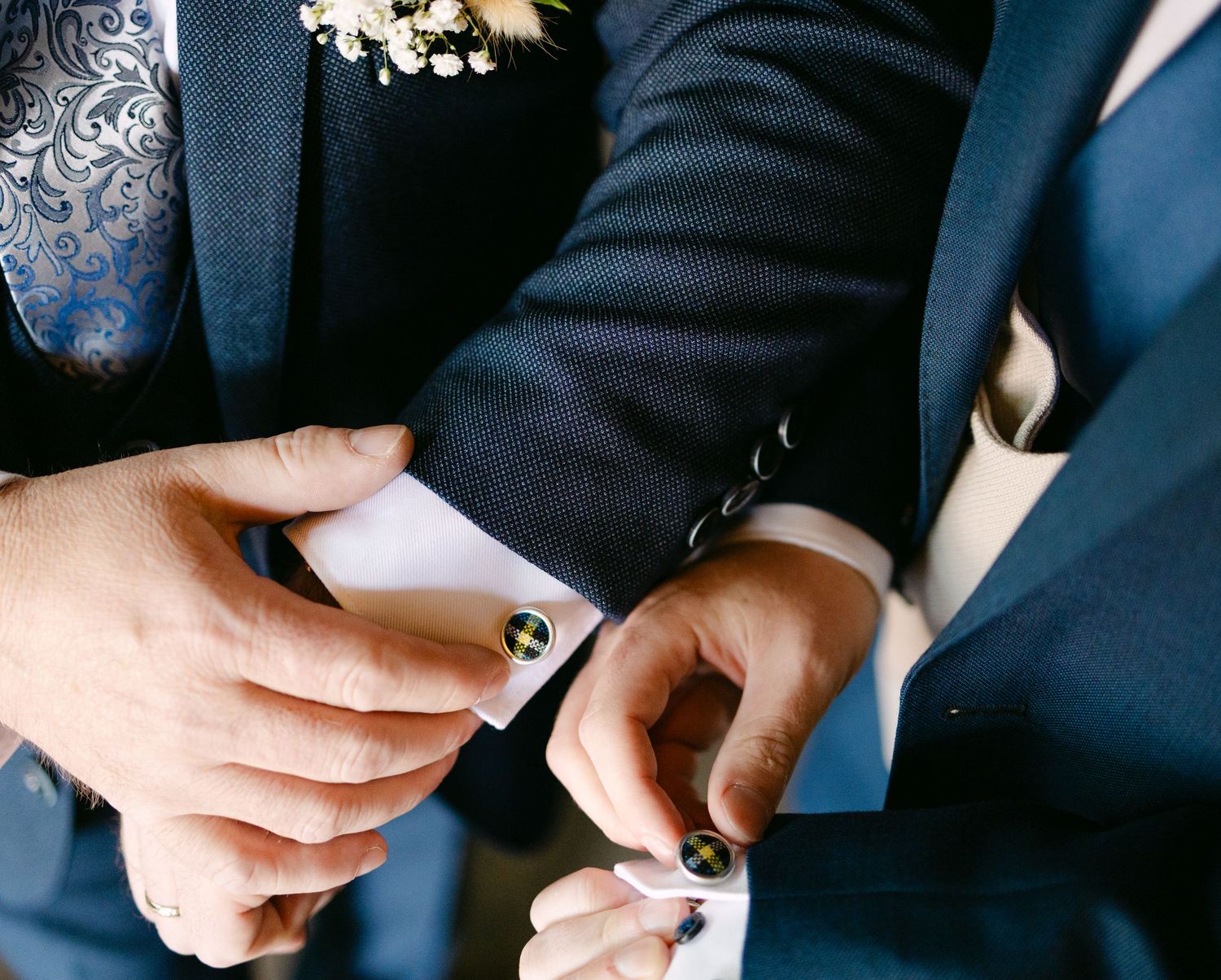 Close-up shots of hands adjusting suit buttons and cufflinks.
