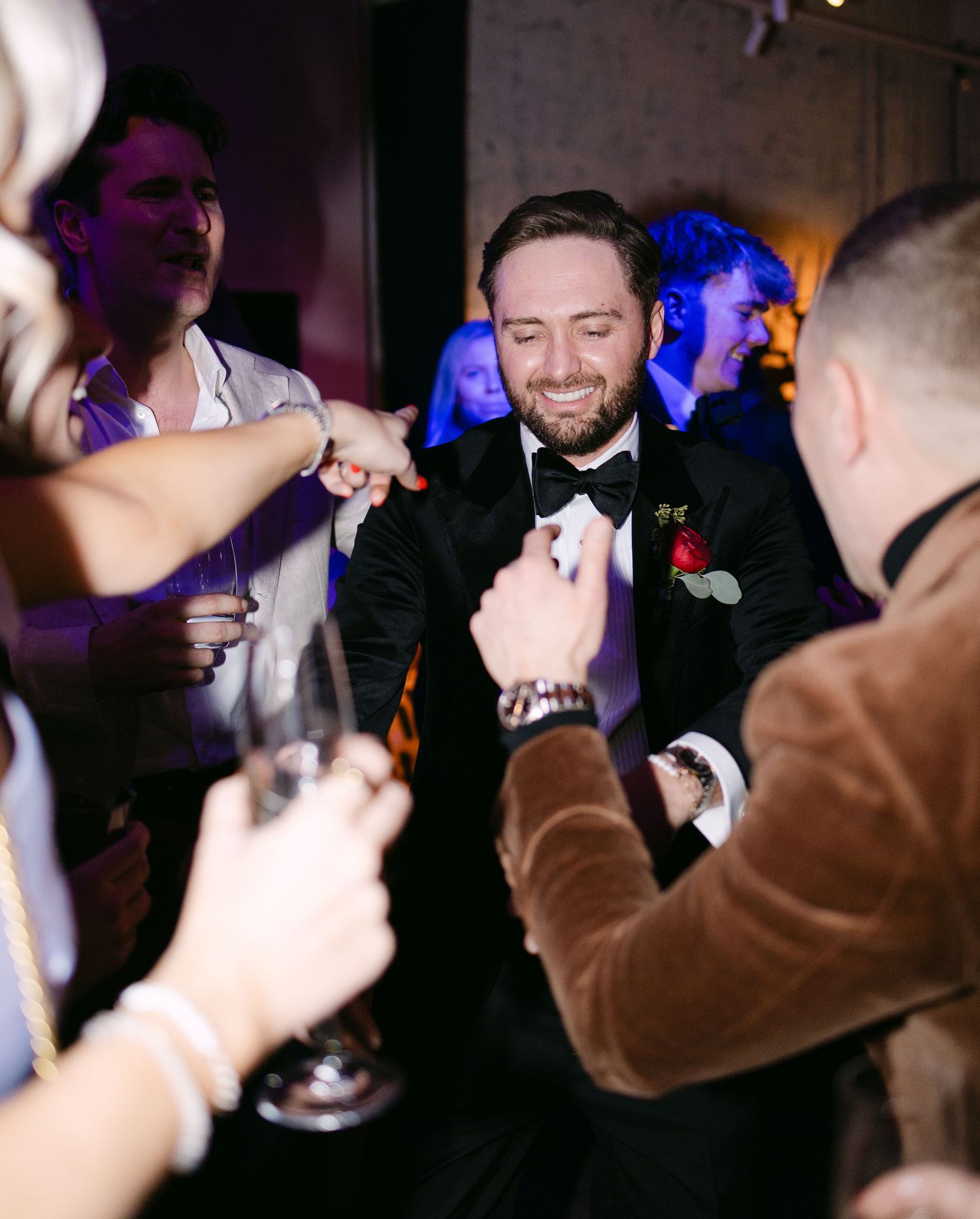 Wedding guests capture photos of the celebration on their phones in dark reception venue.