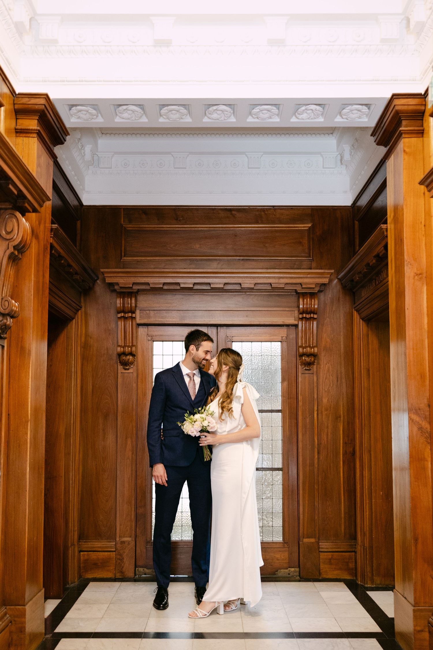 Couple smiling at each other in dark wood panelled hallway at Marylebone Town Hall