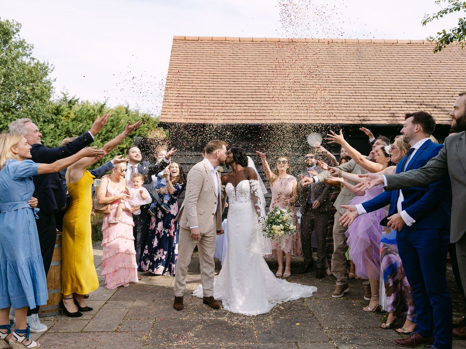 Wedding guests throwing confetti during a joyous outdoor celebration.
