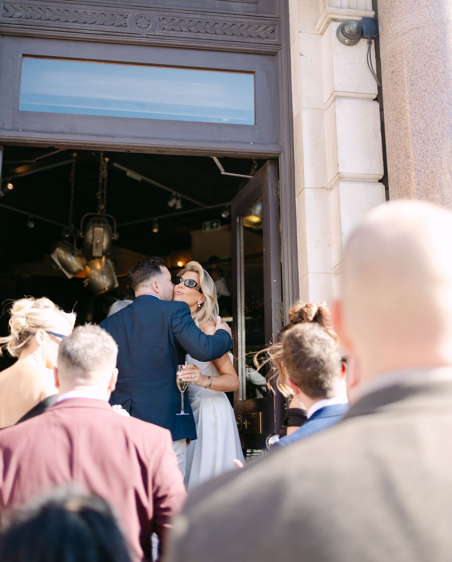 A crowd of formally dressed guests gathered outside a venue entrance.