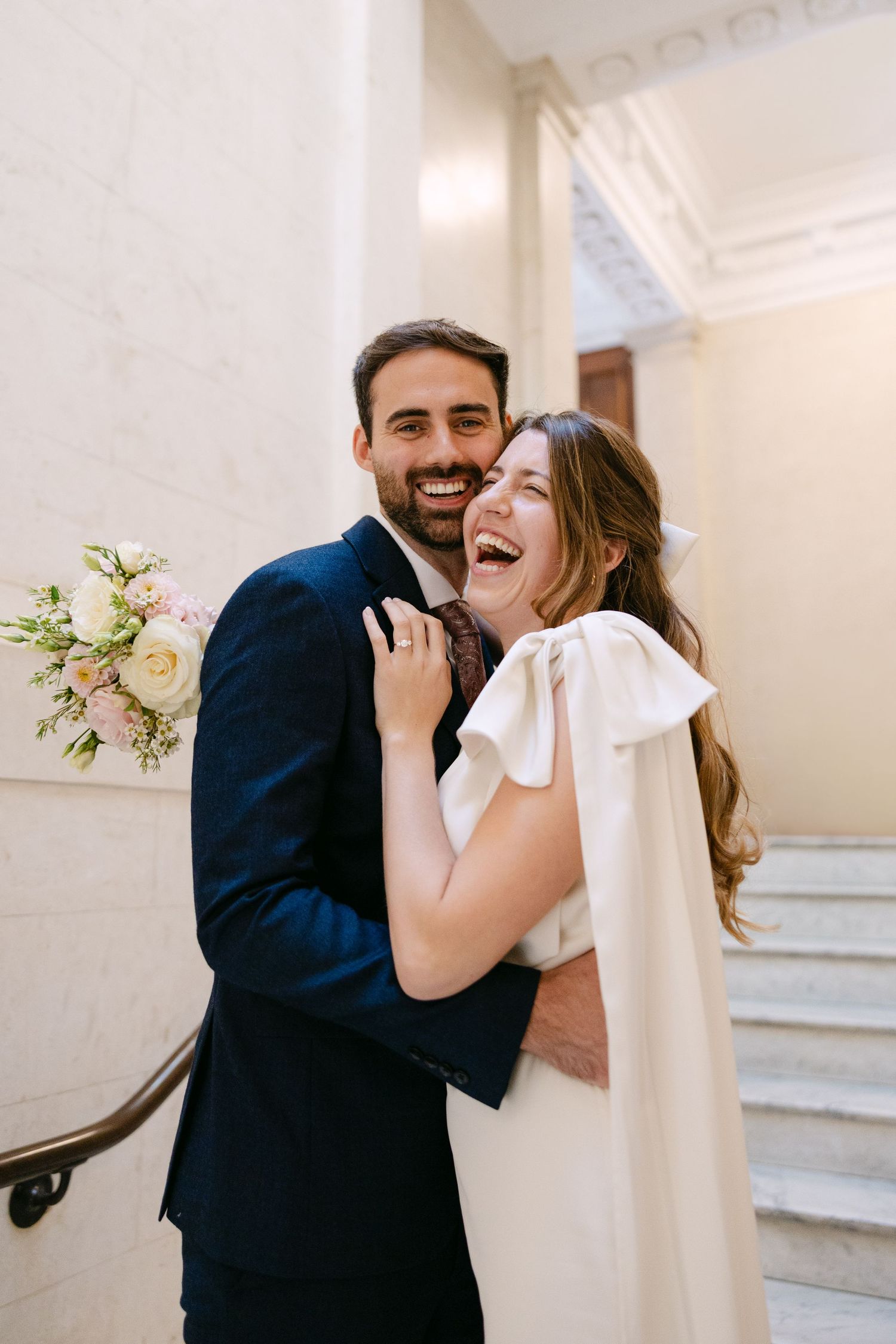 Couple laughing together on white marble staircase at The Kensington Hotel London