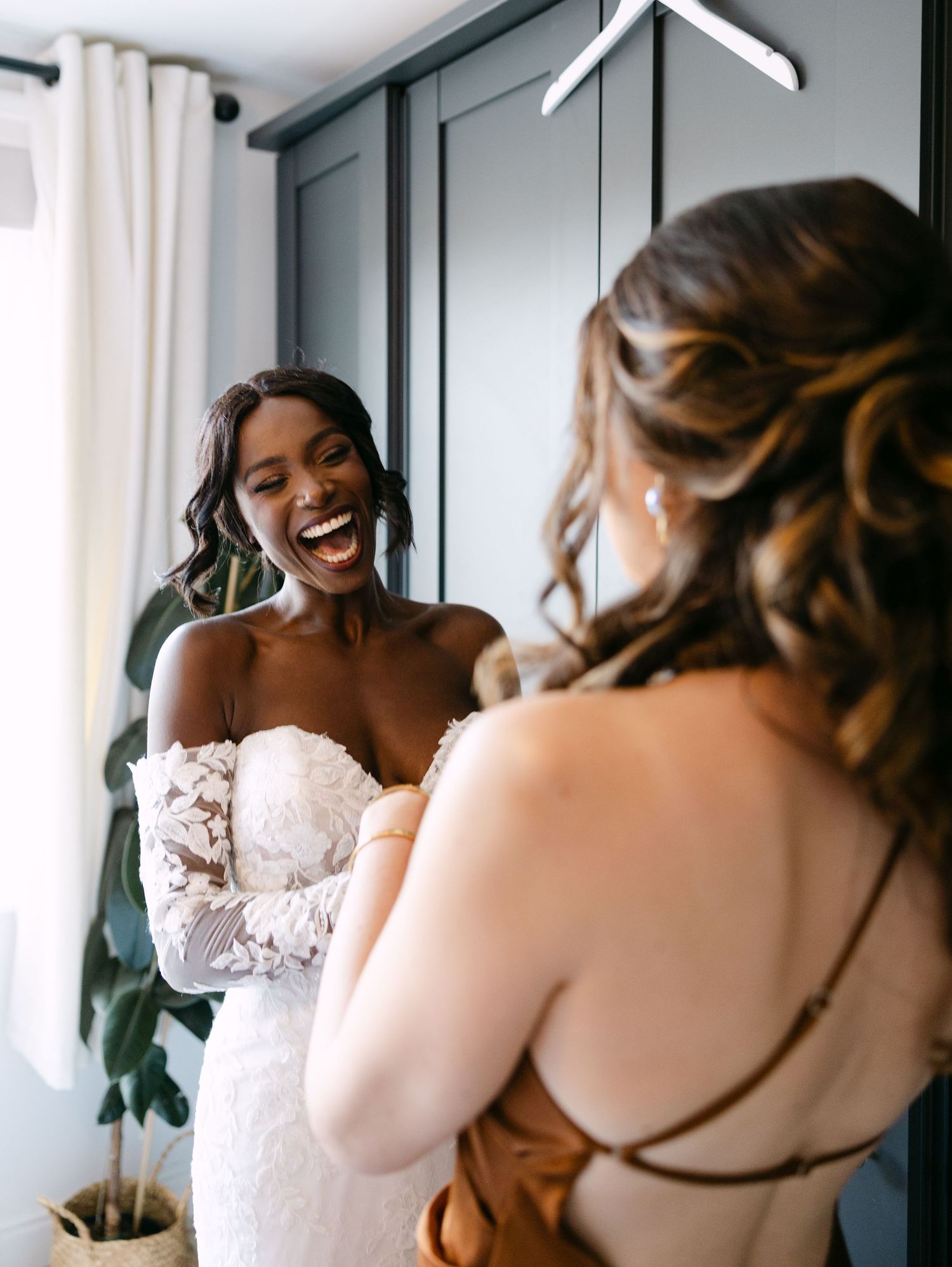 Two people sharing a joyful moment while getting ready in a bright room.