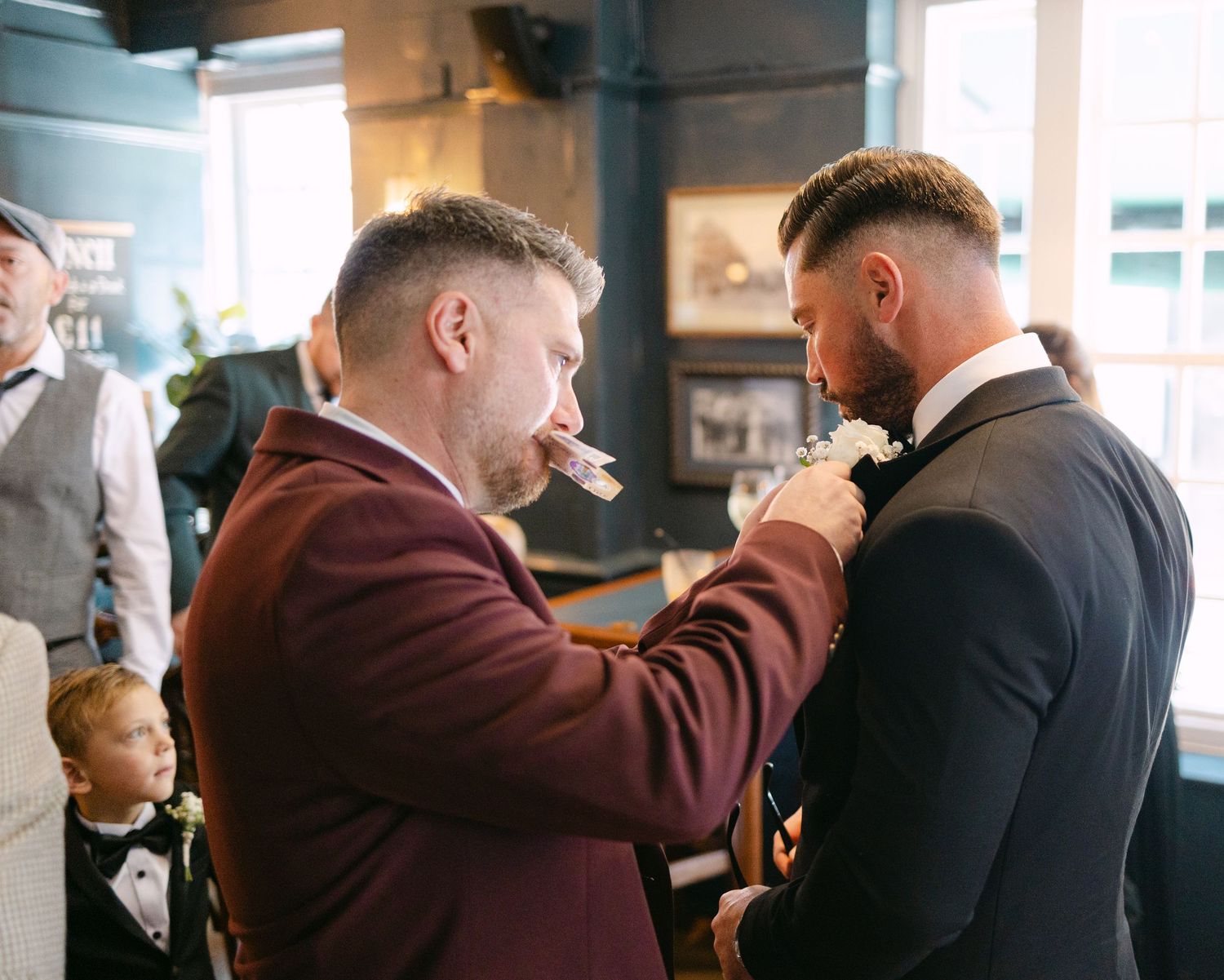 A guest helps adjust another guest's tie before the wedding ceremony.