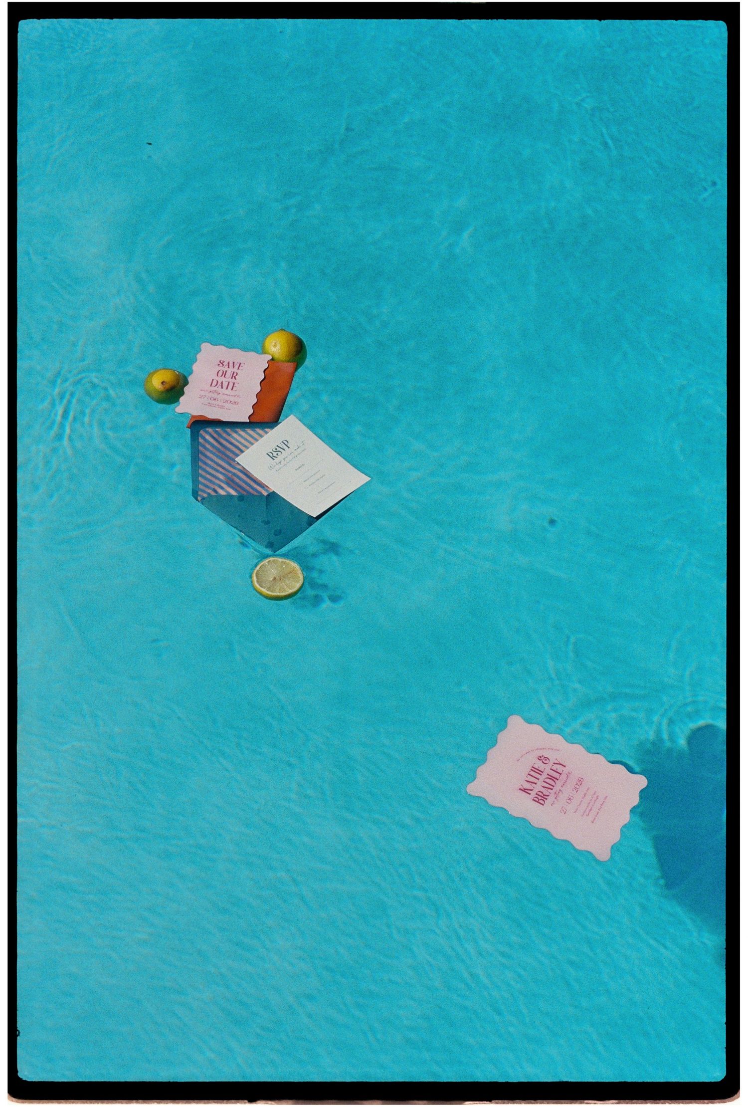 Colorful cards and lime slices floating in a bright turquoise swimming pool on a sunny day.