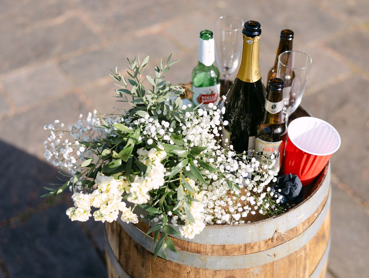 Wine bottles and delicate floral arrangements displayed on a rustic wooden barrel.
