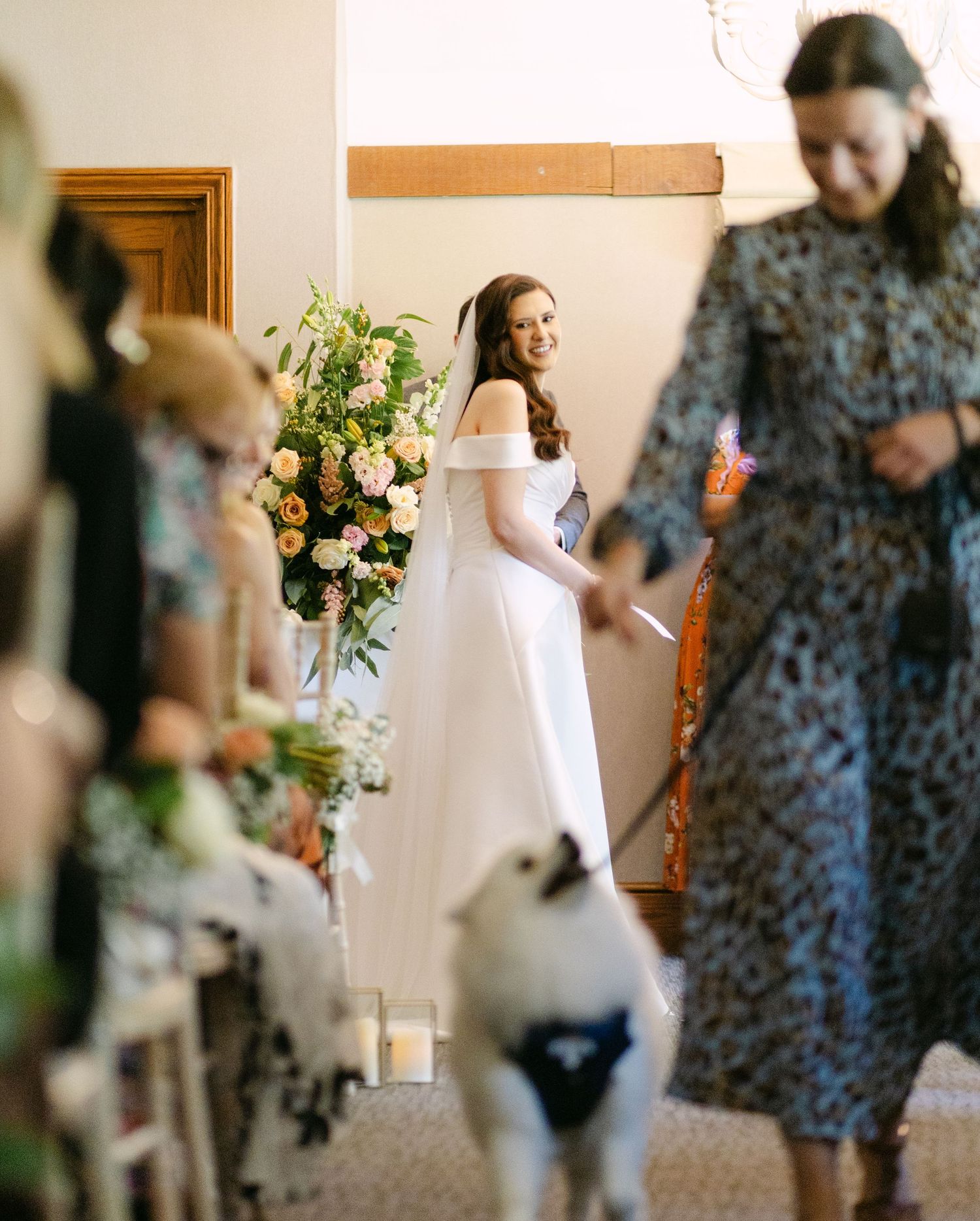 Wedding party members moving through venue with elegant floral arrangements and decor.